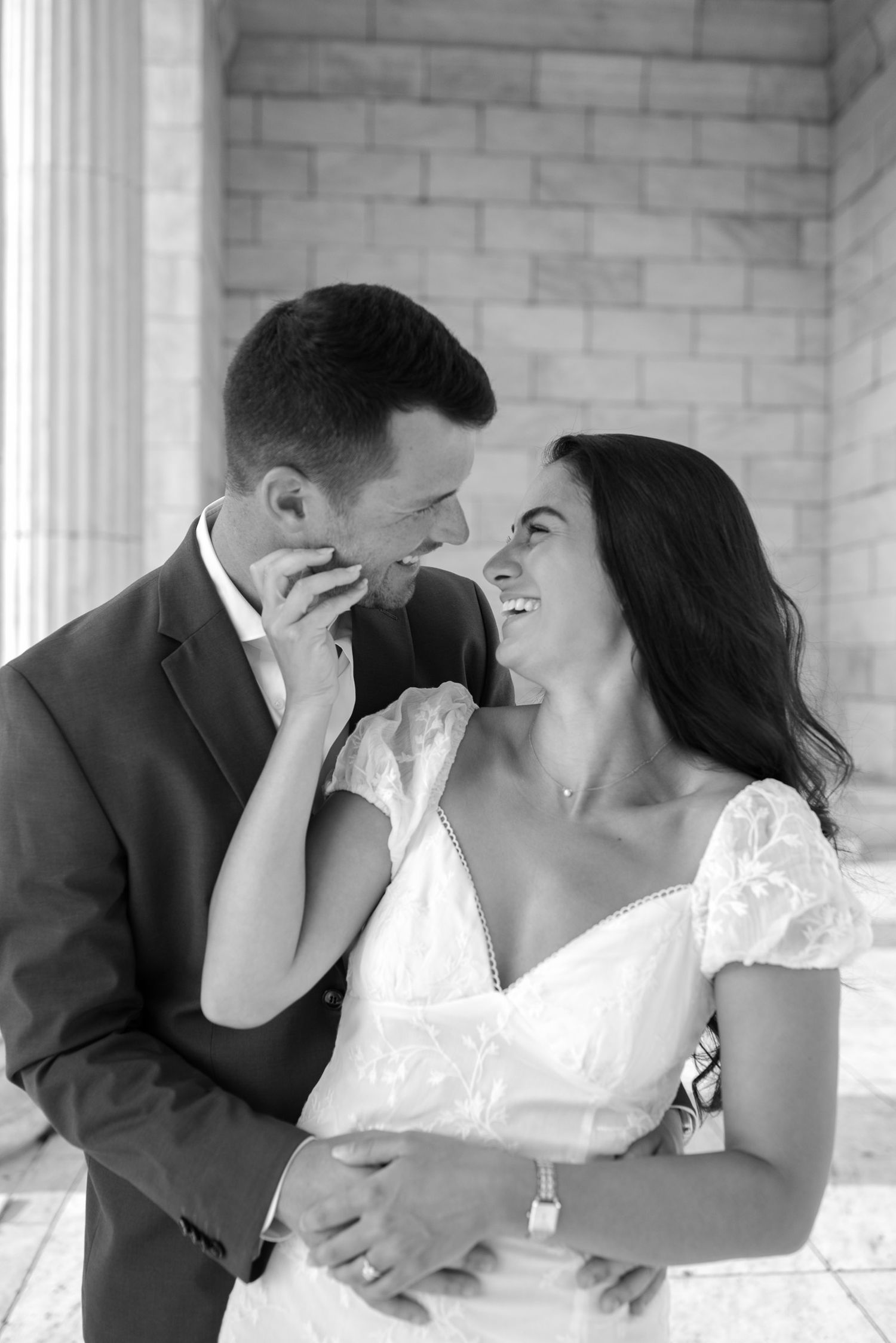 Intimate black and white portraits of couple laughing between classical columns.