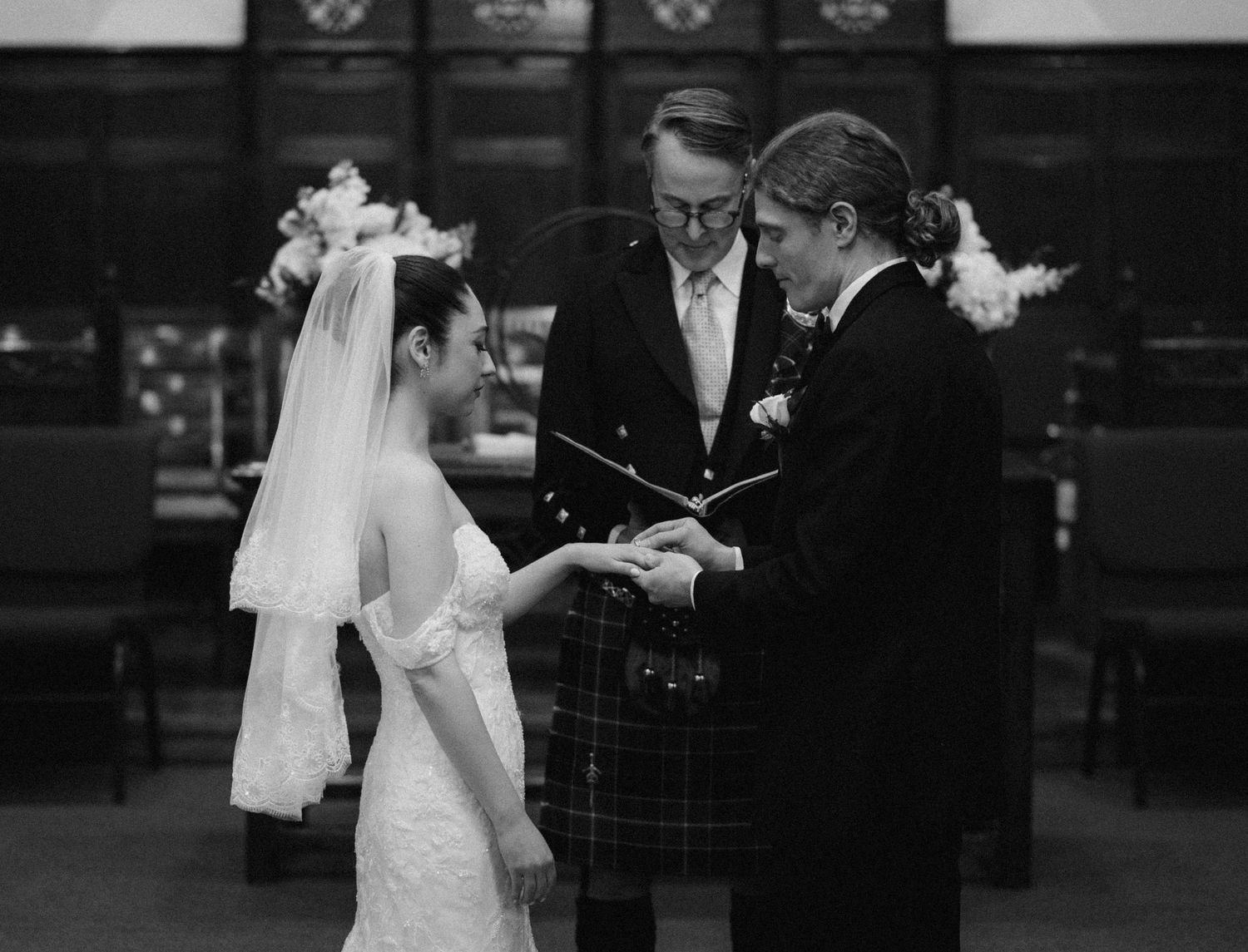 A wedding ceremony takes place in a church with the couple and officiant in traditional attire.