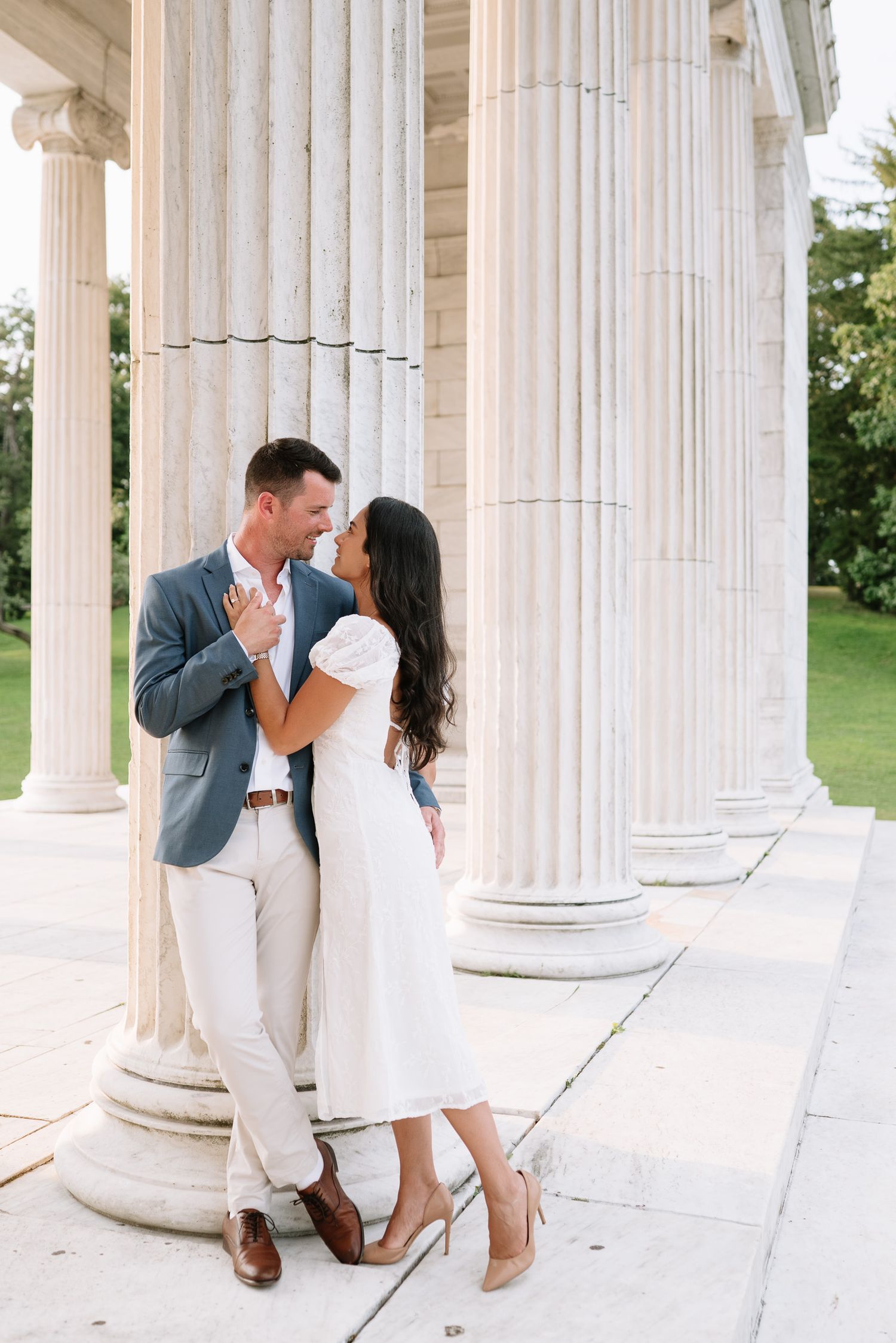 Elegant engagement photography session featuring couple among classical white pillars.