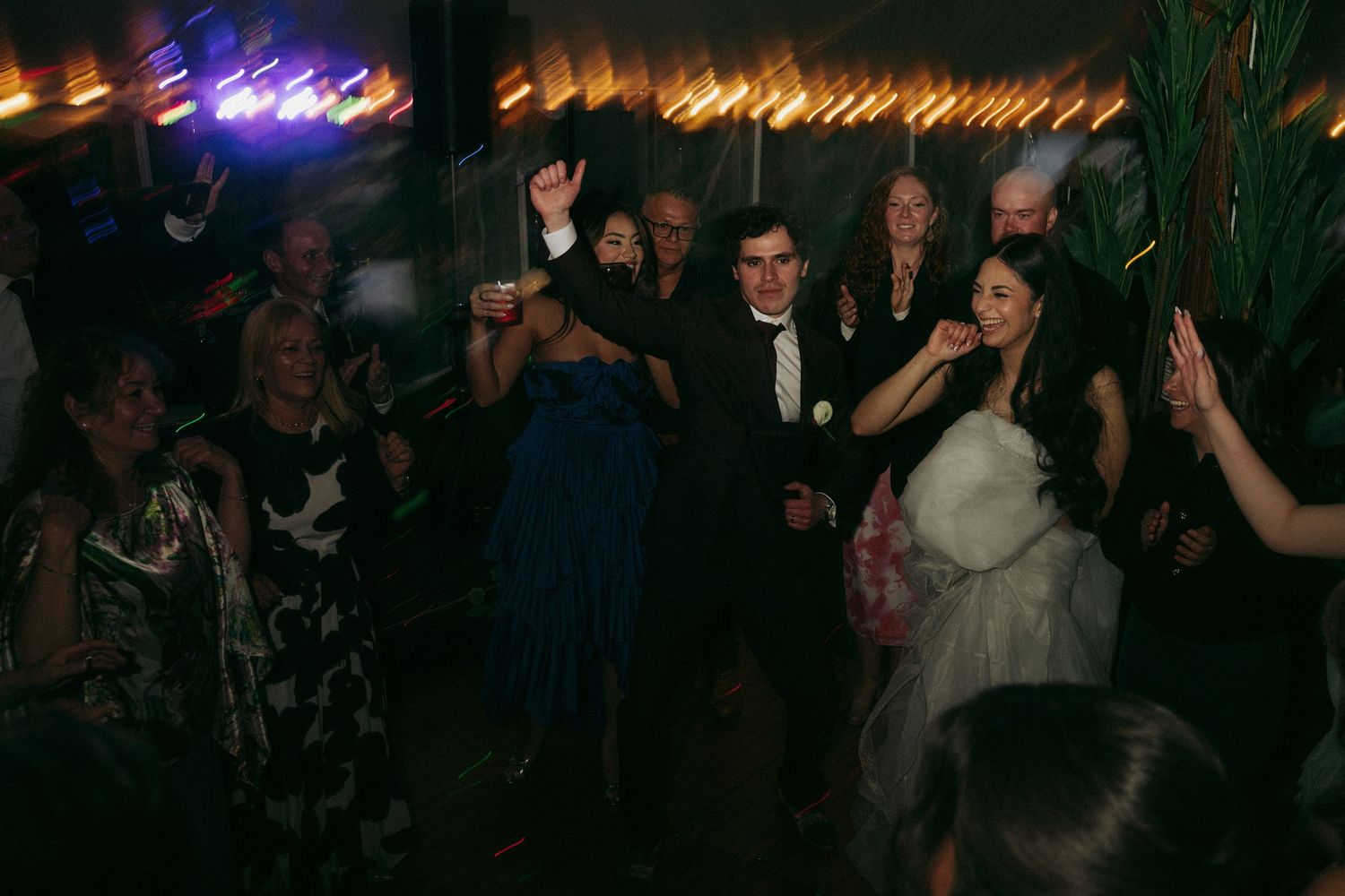 Guests dancing and celebrating at a lively evening wedding reception party on the dance floor.