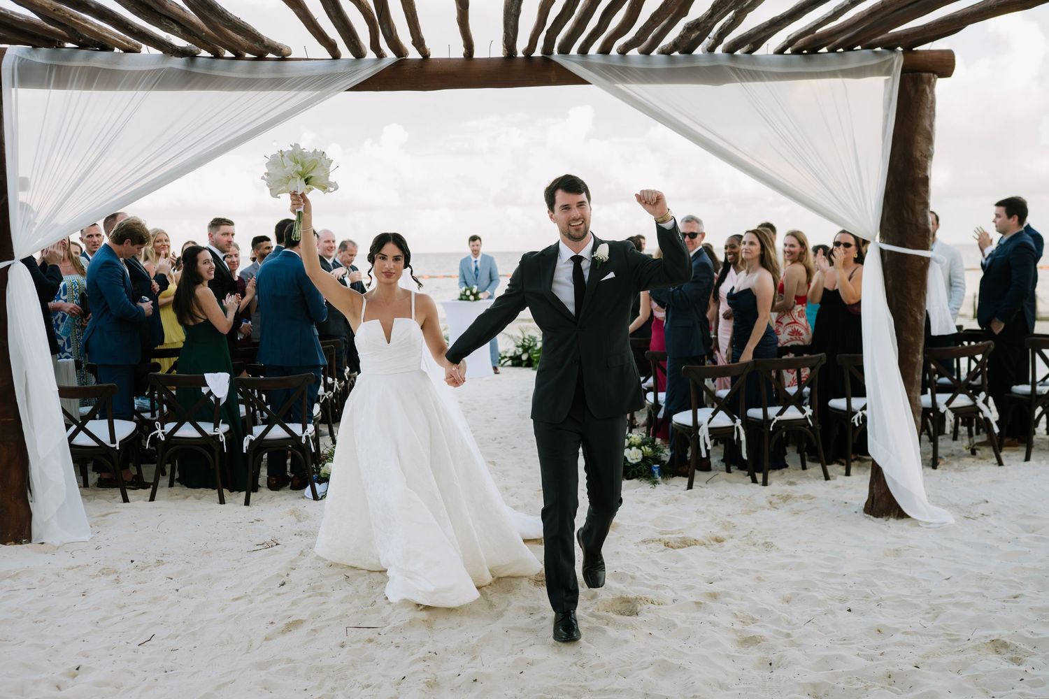 Beachfront wedding ceremony setup with white chairs and canopy overlooking the ocean.