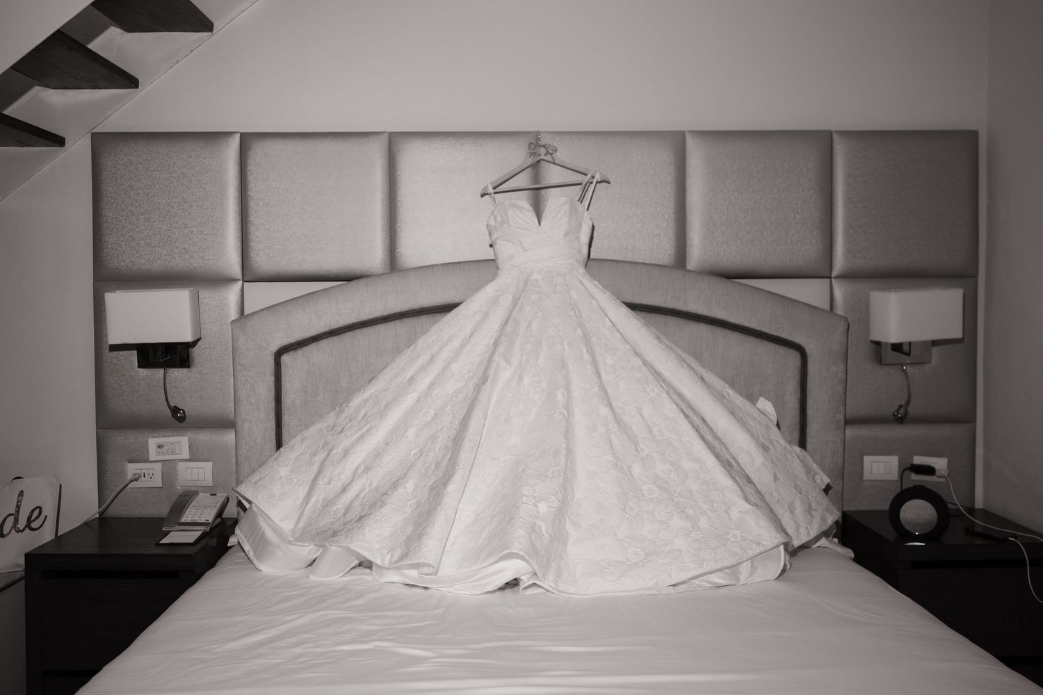 Three identical wedding dresses displayed side by side against a neutral gray wall.