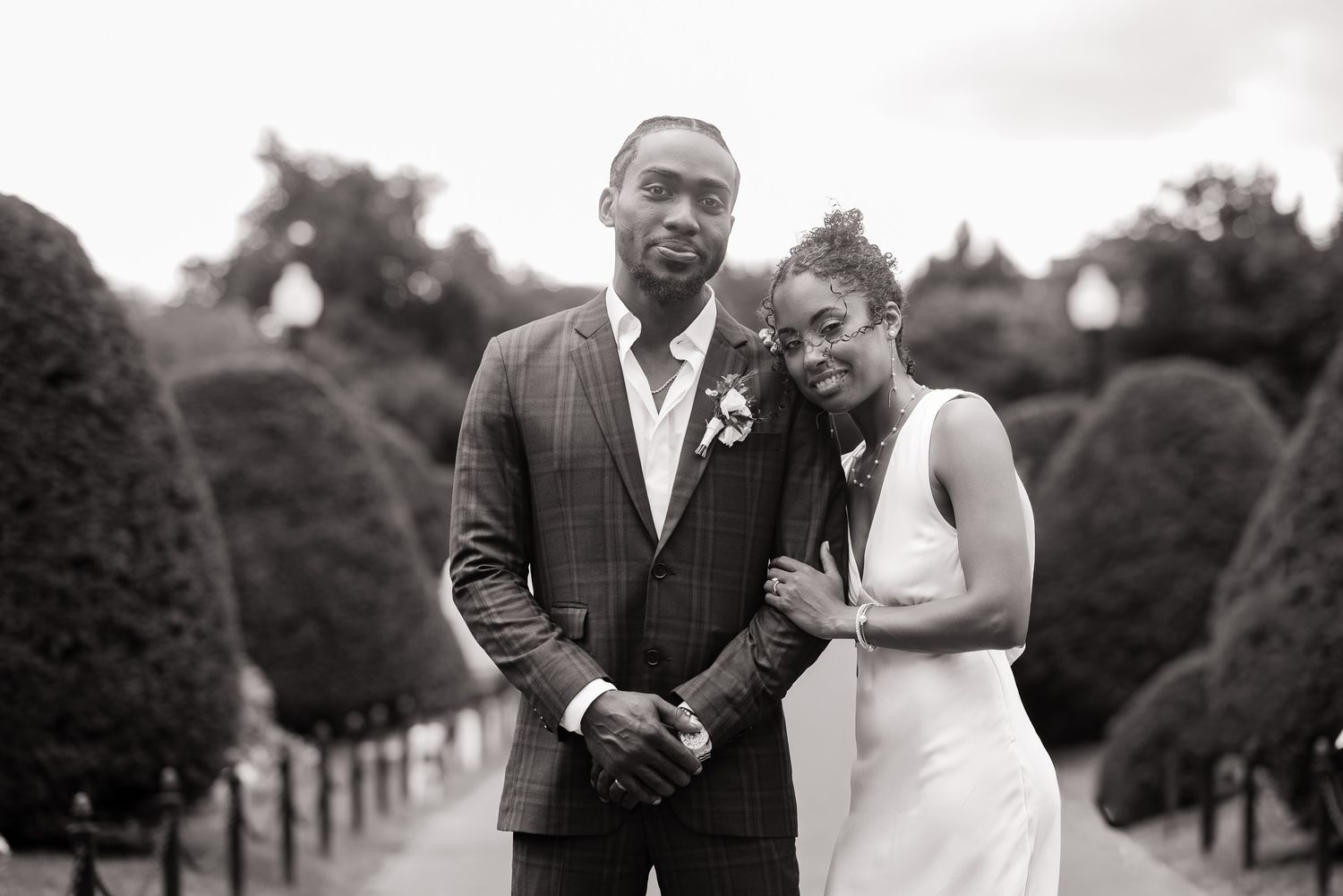 A couple shares a romantic moment together on their wedding day in an outdoor garden setting.