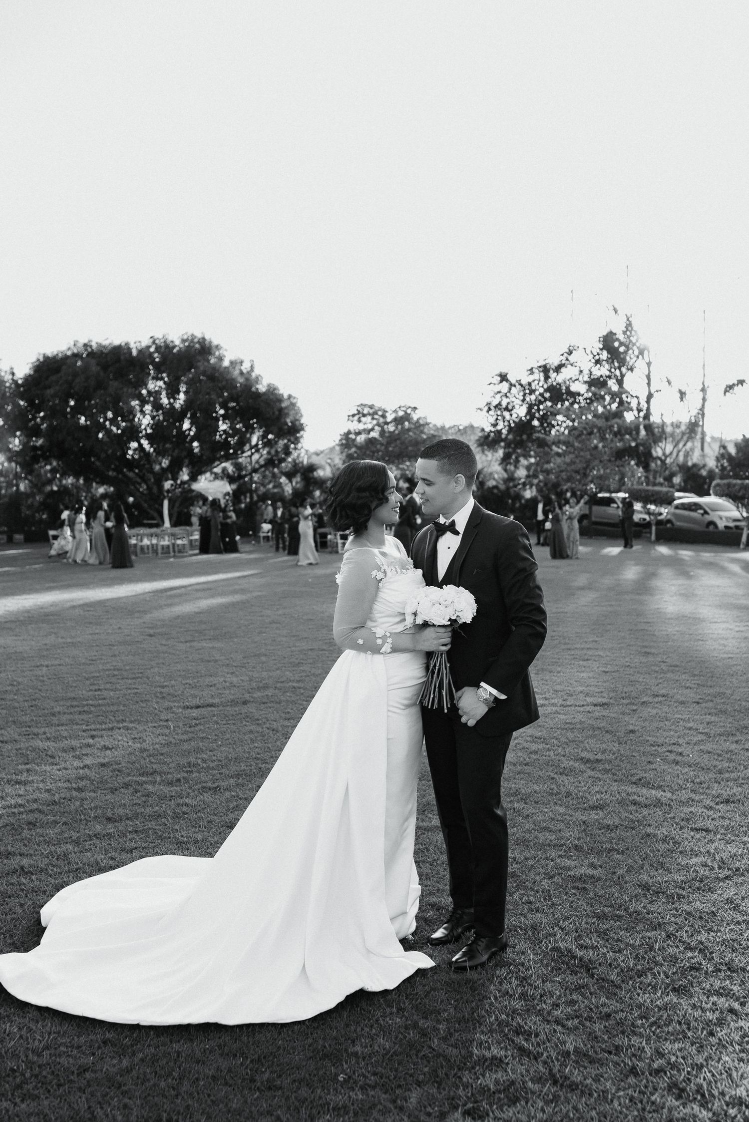 Wedding couple poses on a grassy field with a flowing white wedding dress.