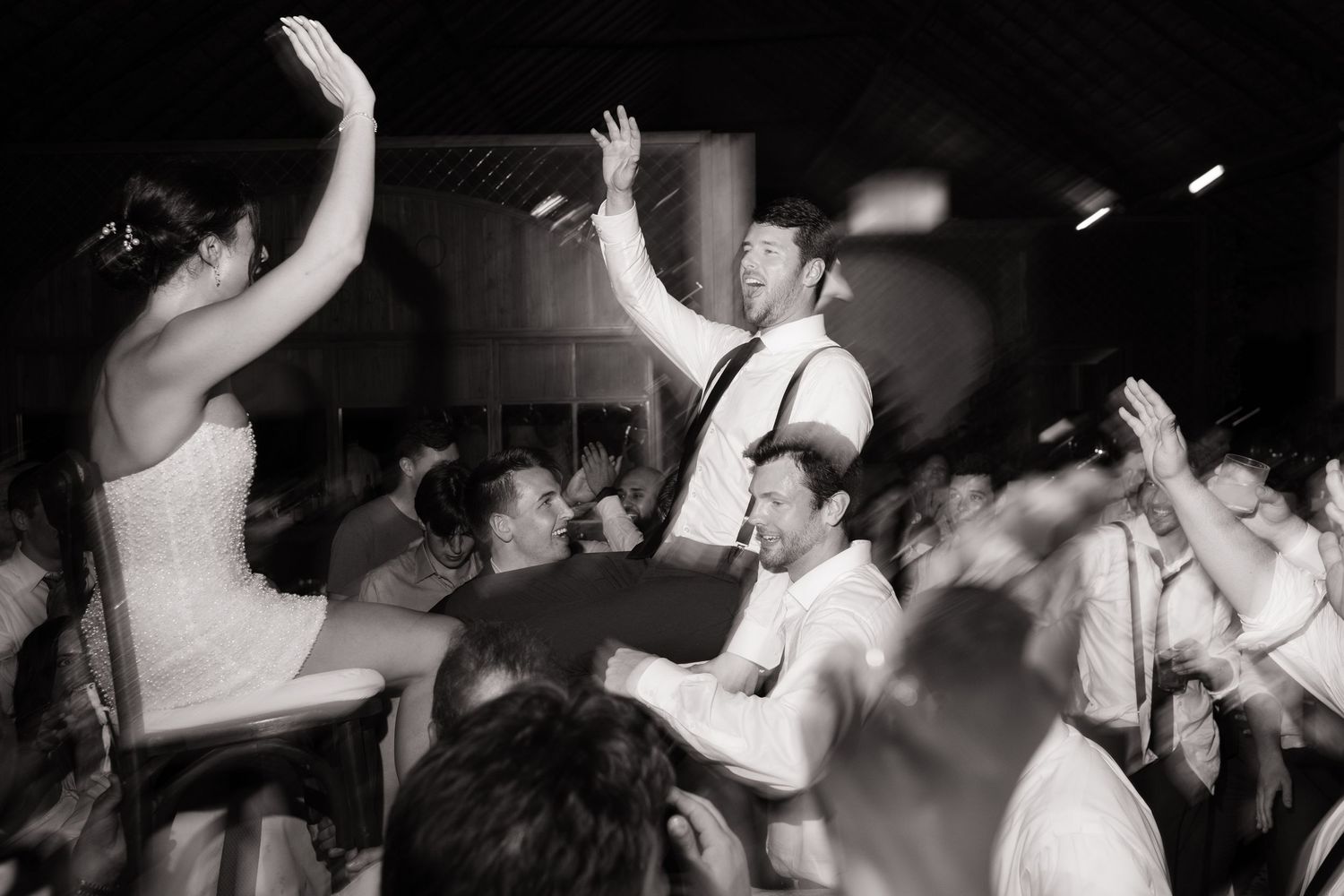 A crowd of party guests dancing and celebrating with sparklers held high in a dimly lit venue.
