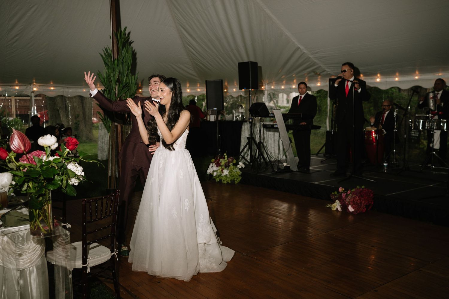 A bride and groom share their first dance under a white tent at their wedding reception.