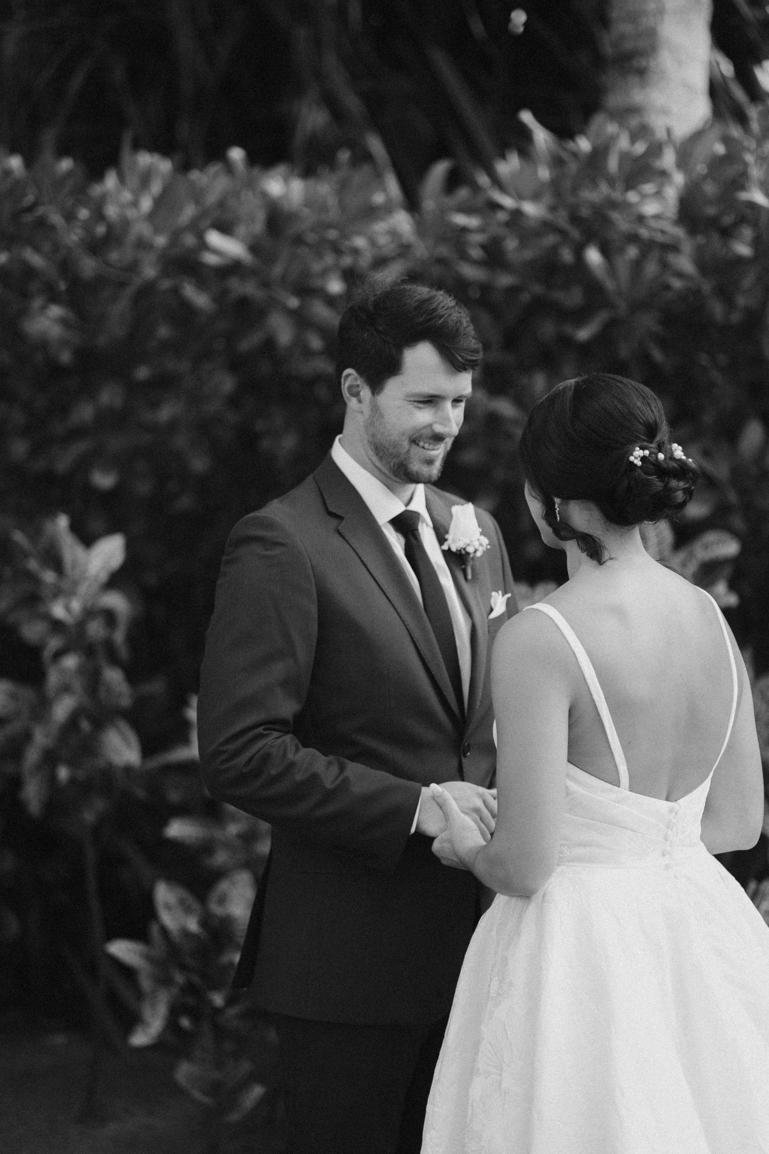 A black and white wedding photo captures a tender first look moment between newlyweds.