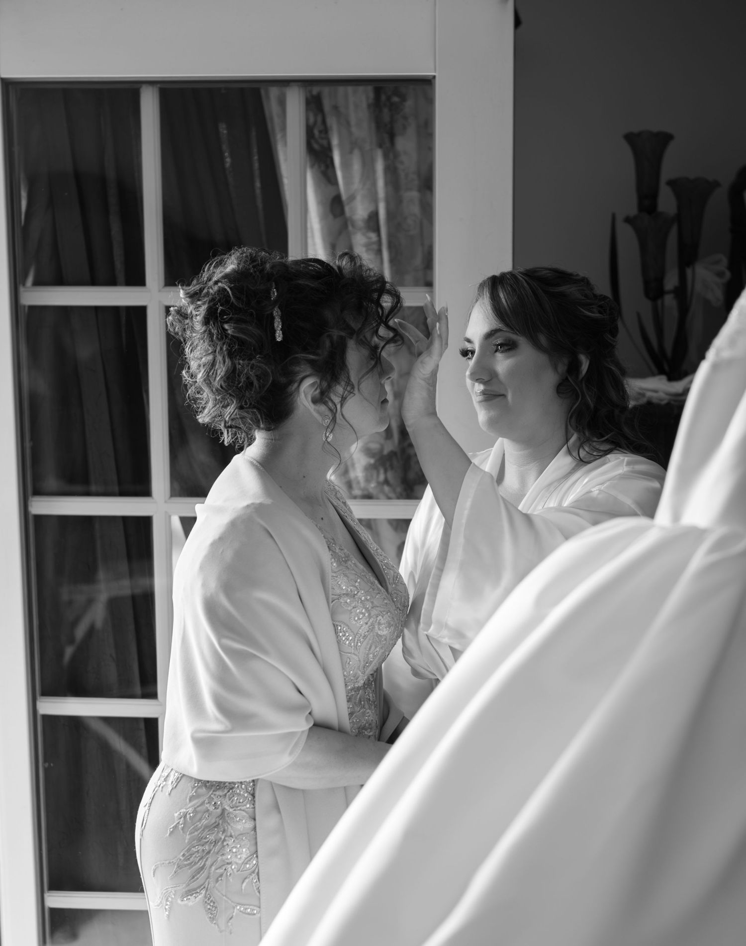 A black and white photograph showing a group of women in white dresses preparing for a wedding ceremony.