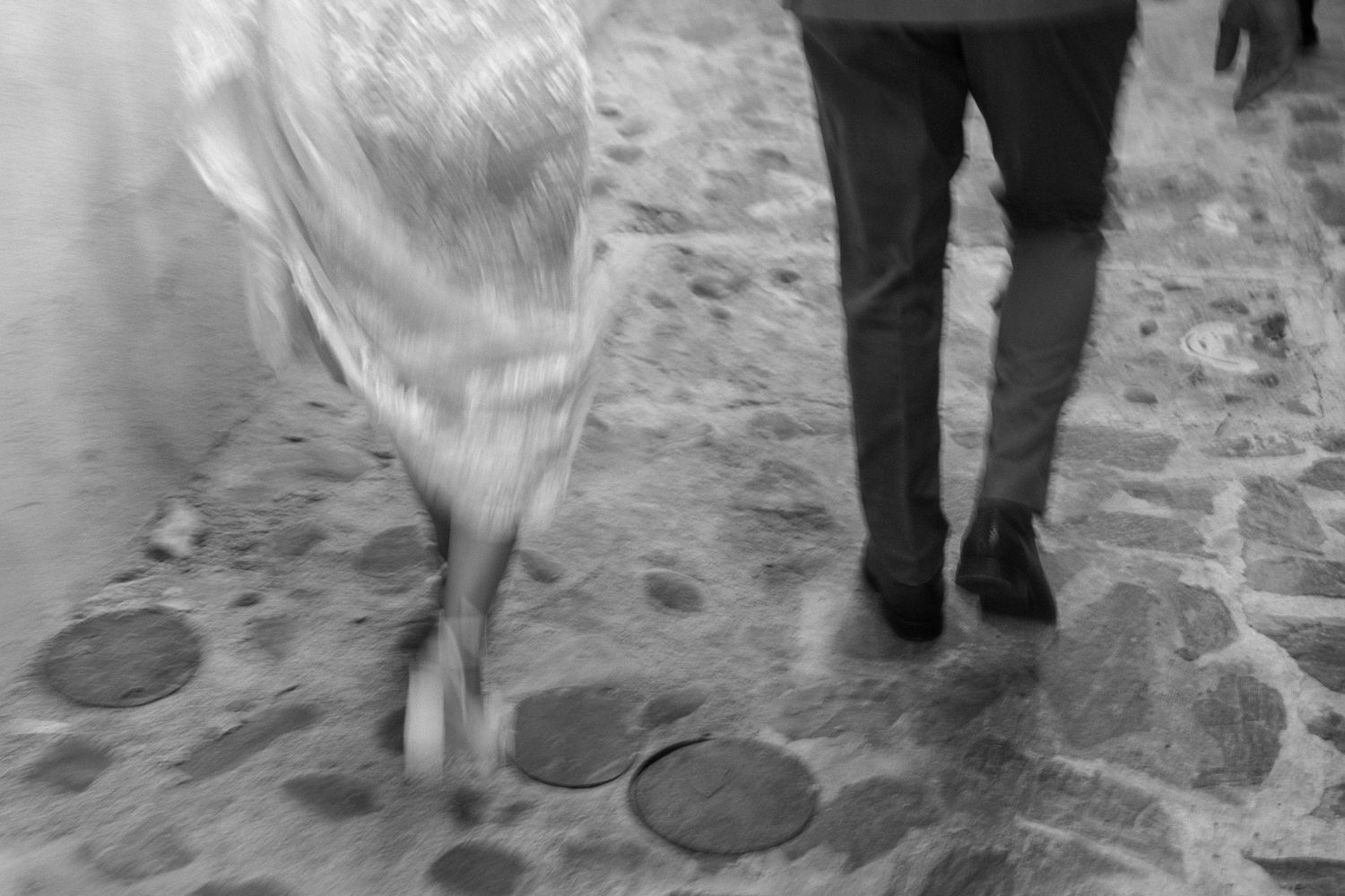 Motion blur of wedding dress and legs walking on stone pathway.