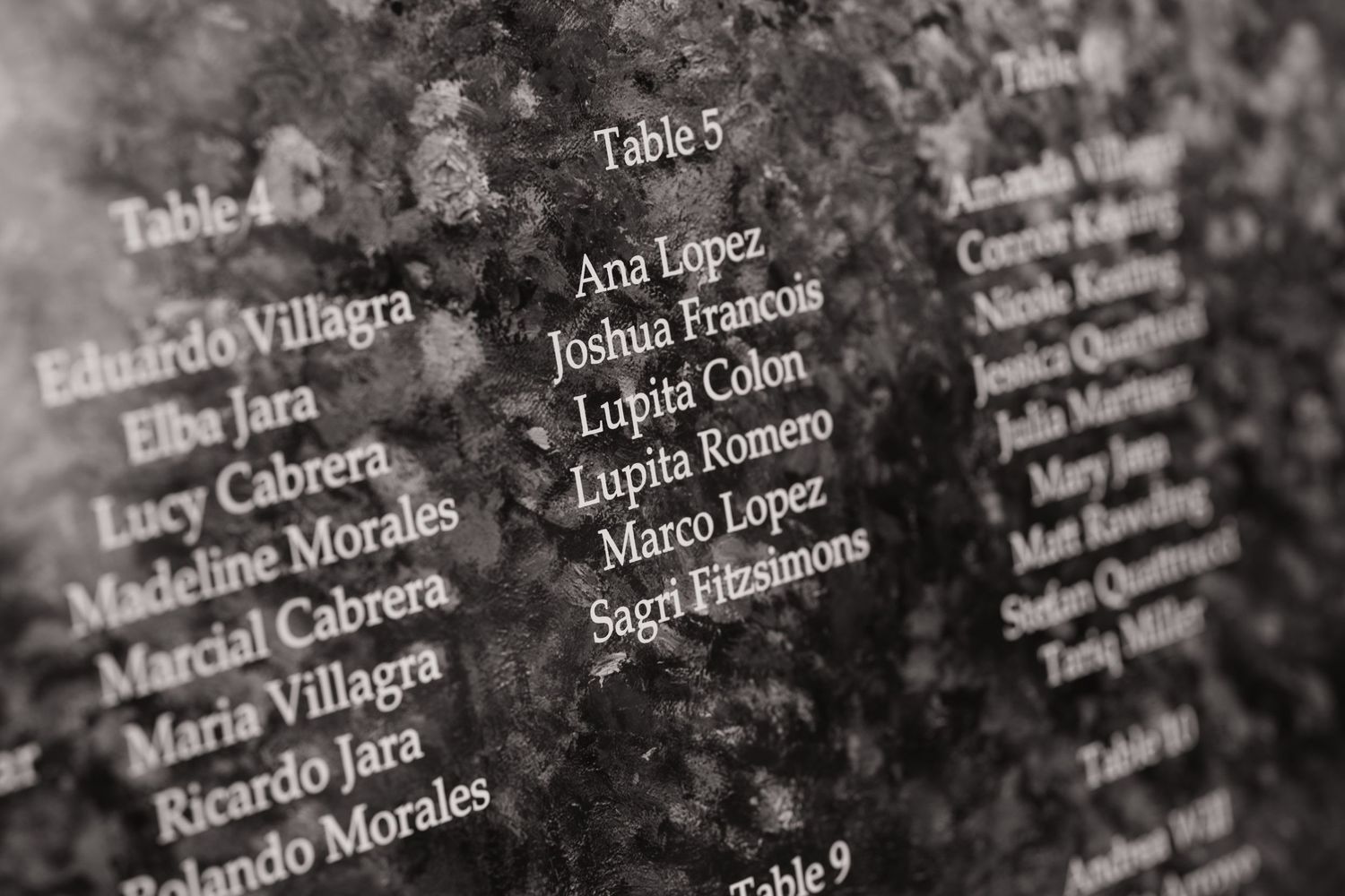Black stone wedding seating chart with engraved guest names organized by table numbers.