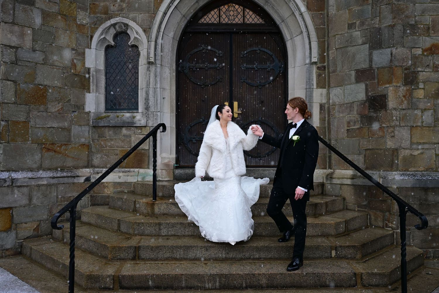 Newlyweds walking down stone church steps after their ceremony.