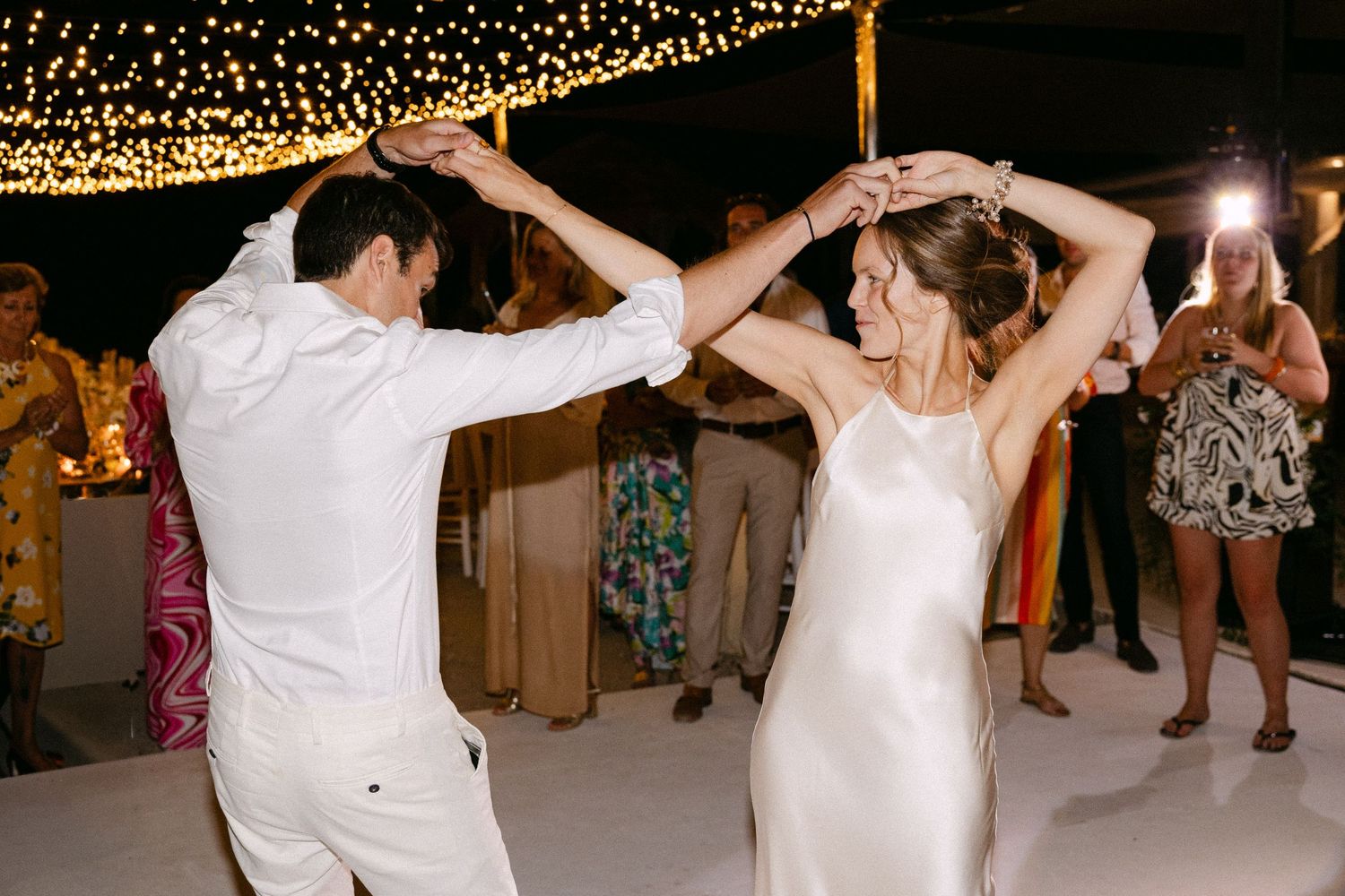 a bride and groom locking hands in dance at night
