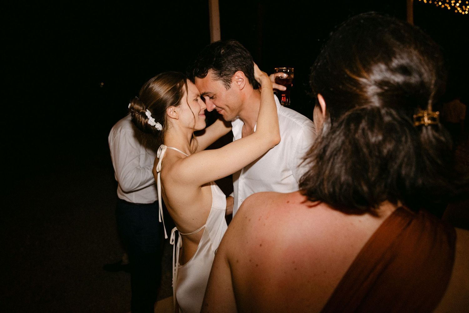 a bride and groom dancing with each other during the open-air wedding party of their Spetses wedding, bringing their foreheads together