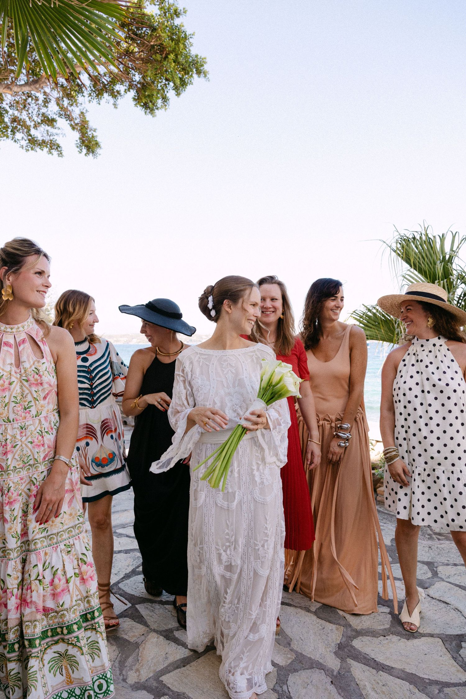 a bride holding a white Lillies bouquet walking among her friends and smiling at each other