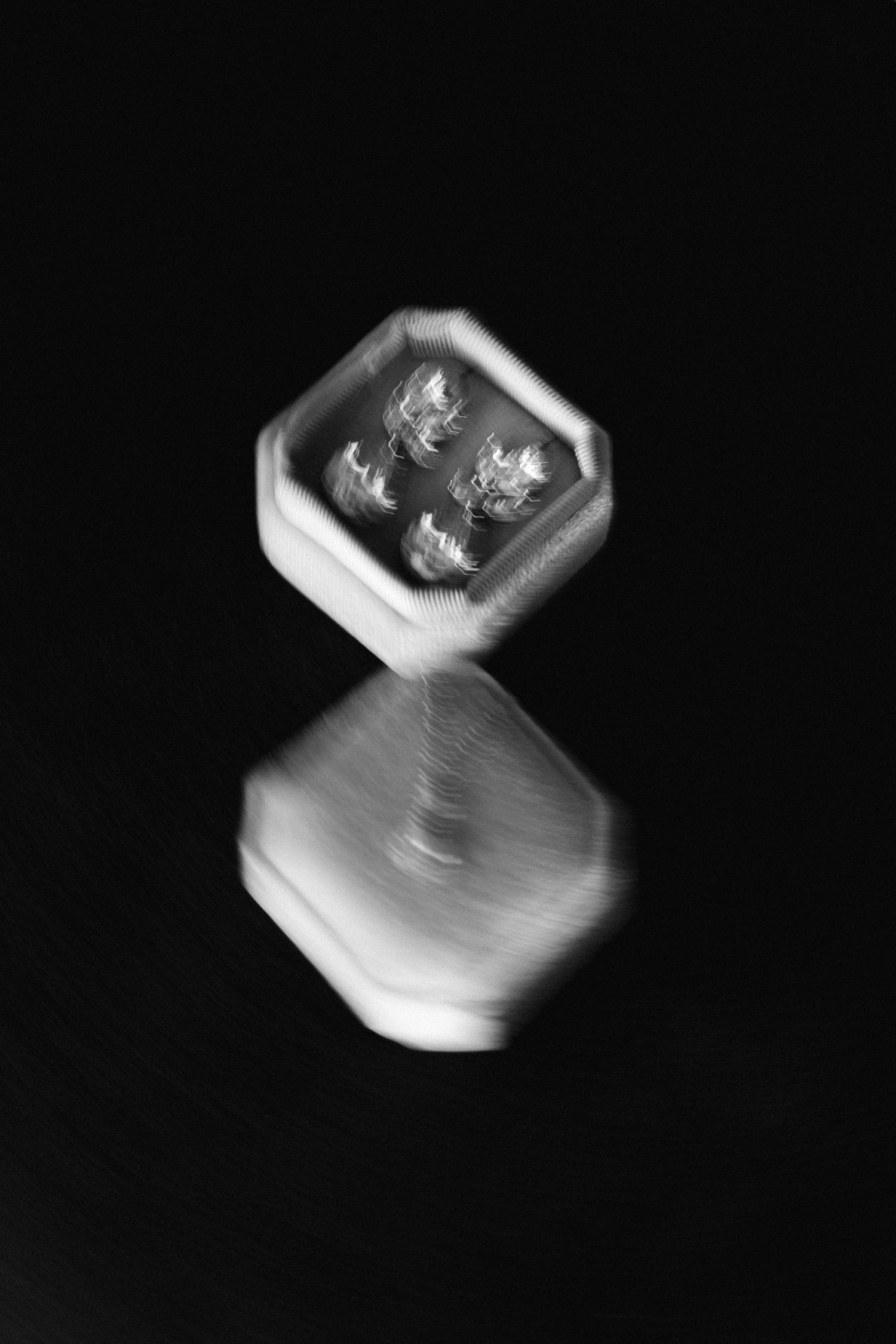 a motion blurred black and white photo of a wedding earring case against a black background - the photo shows the earrings inside the case