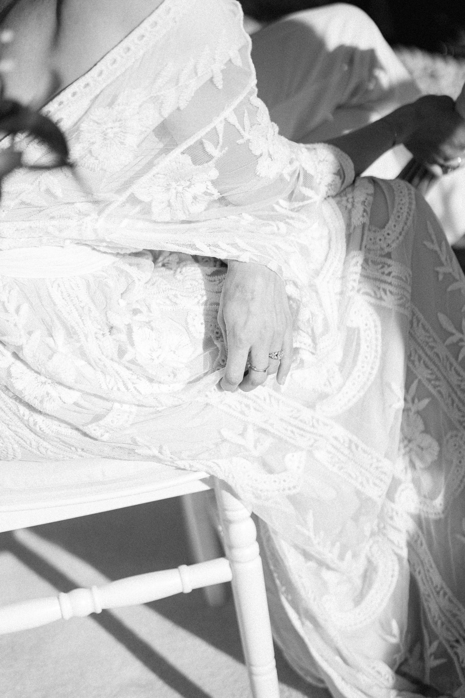 a black and white photo of a bride's hand resting on her wedding dress