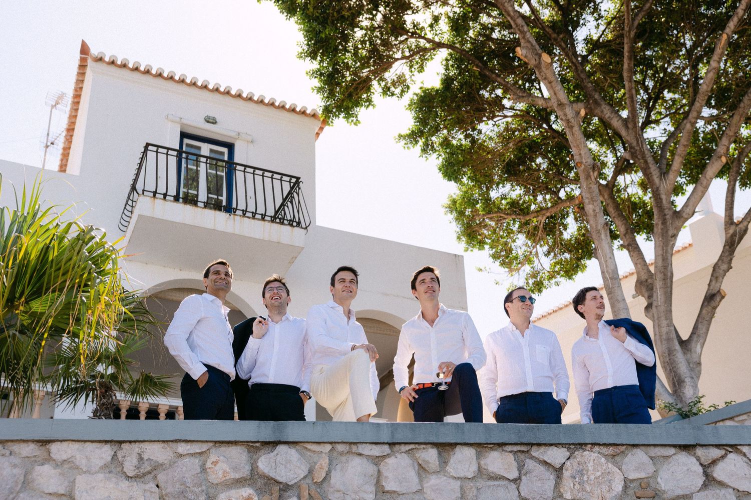 six groomsmen posing in an editorial way in front of a villa