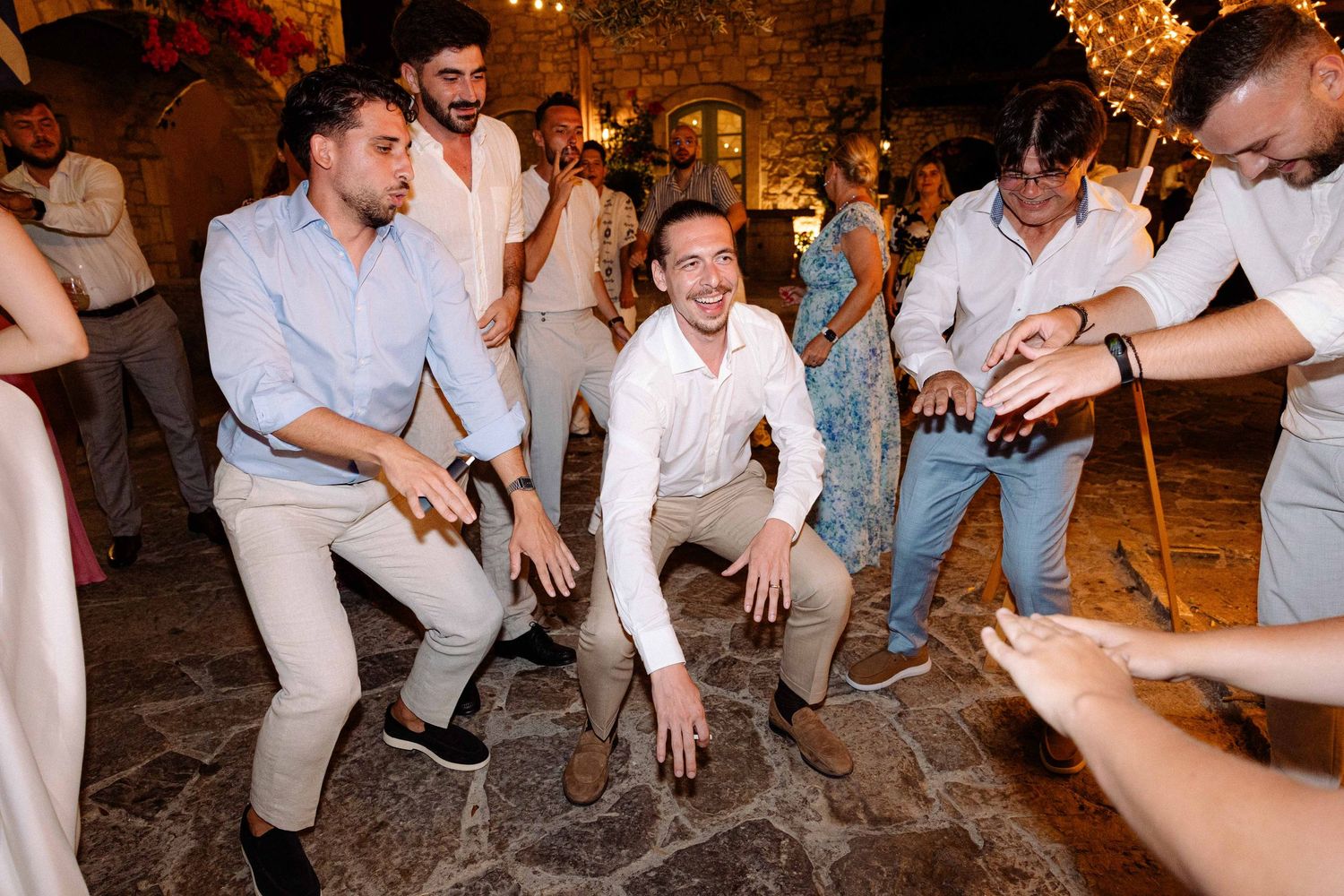 a groom dancing with his friends during an outdoors summer party
