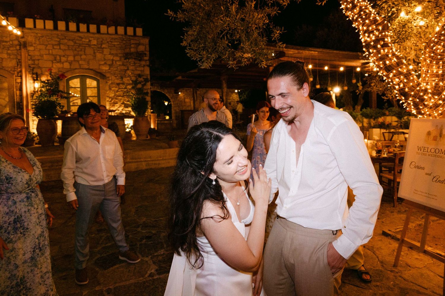 a bride and groom dancing and laughing in their open air reception in Crete