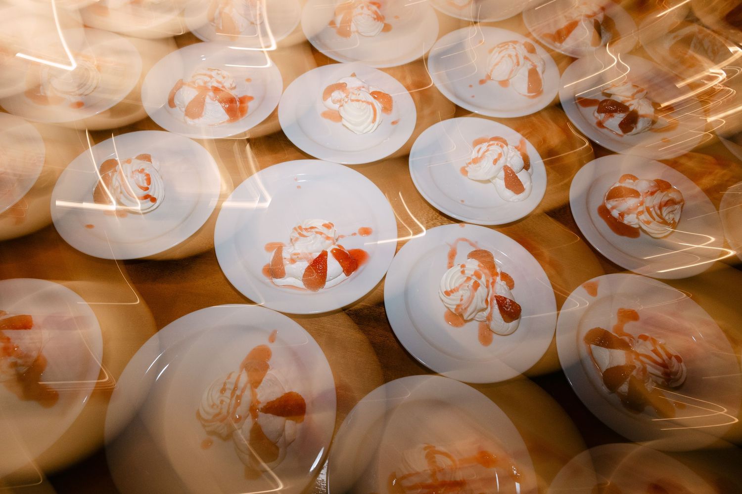 a motion-blur photo of wedding cake with red syrup cut and divided into around 20 plates