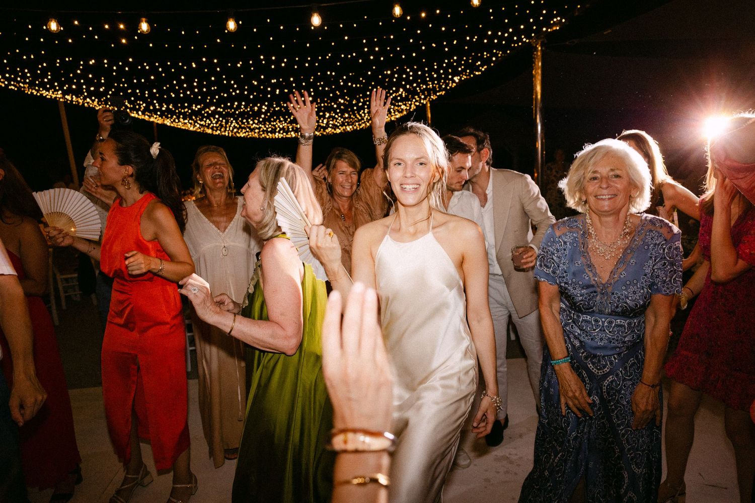 a smiling bride dancing among guests during an open-air wedding party of her Spetses wedding