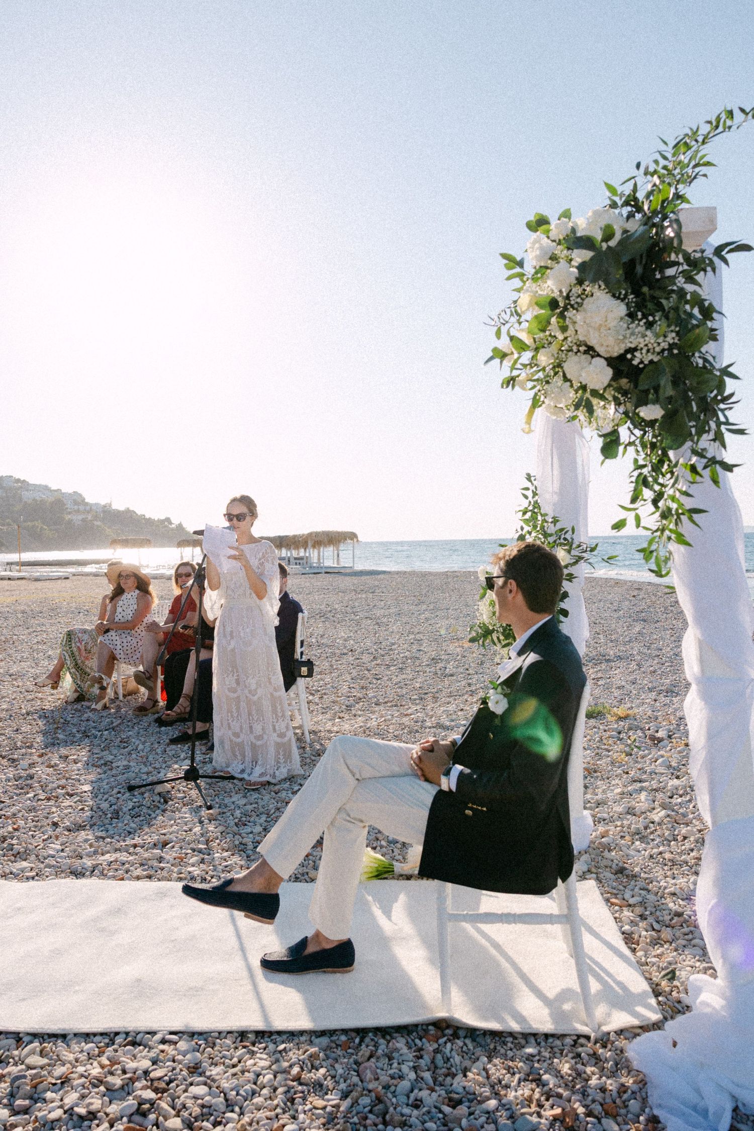 a bride reading a speech and looking at the groom during their beach wedding ceremony