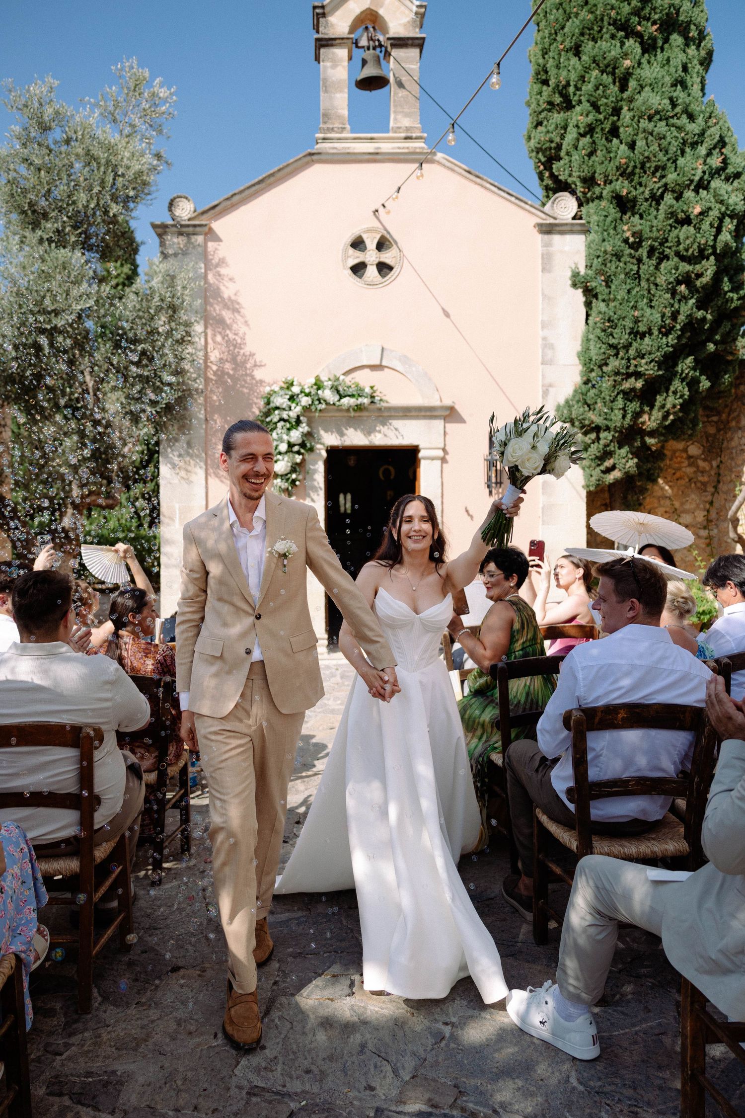 A bride and groom right after their wedding ceremony walking hand in hand among guests in their micro wedding in Agreco Farm in Crete Greece