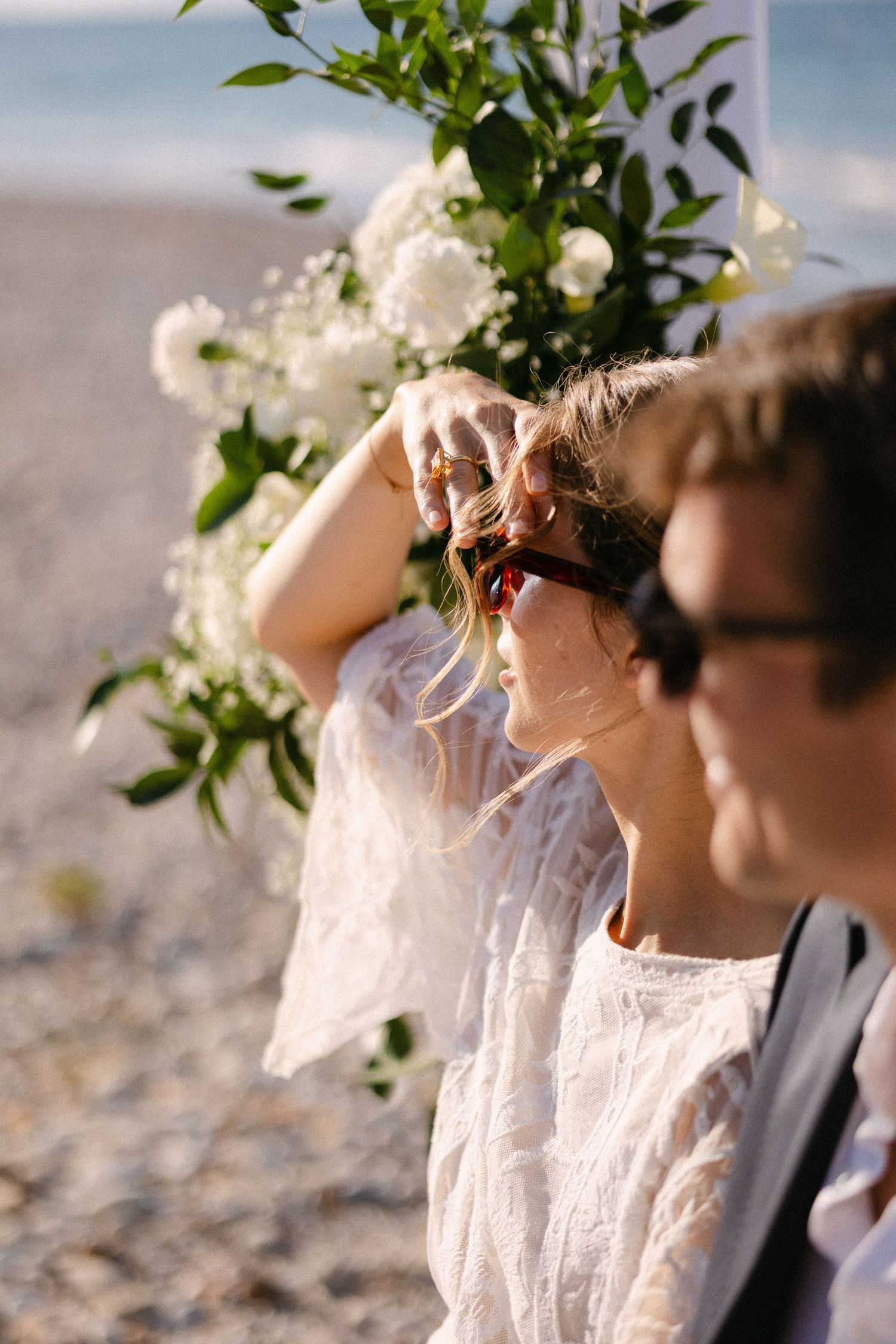 a close up portrait of a bride and groom wearing shades with white flowers as backdrop