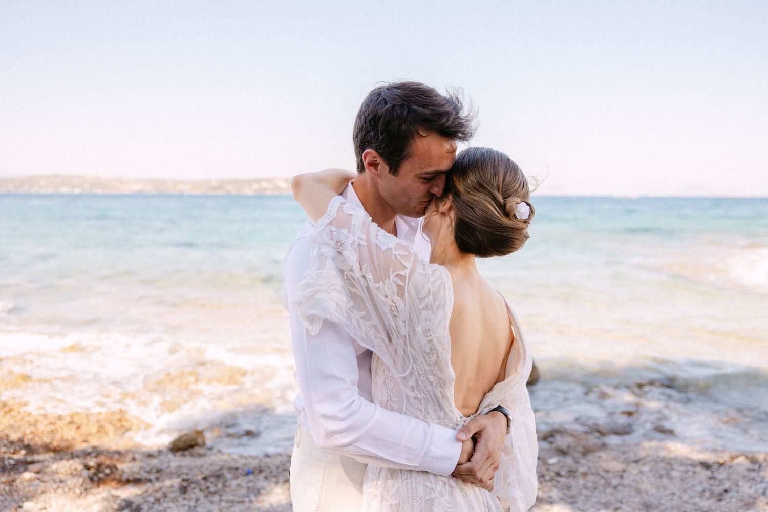 a man and a woman in a close embrace where the man is wispering in the woman's ear - they are standing in a beach