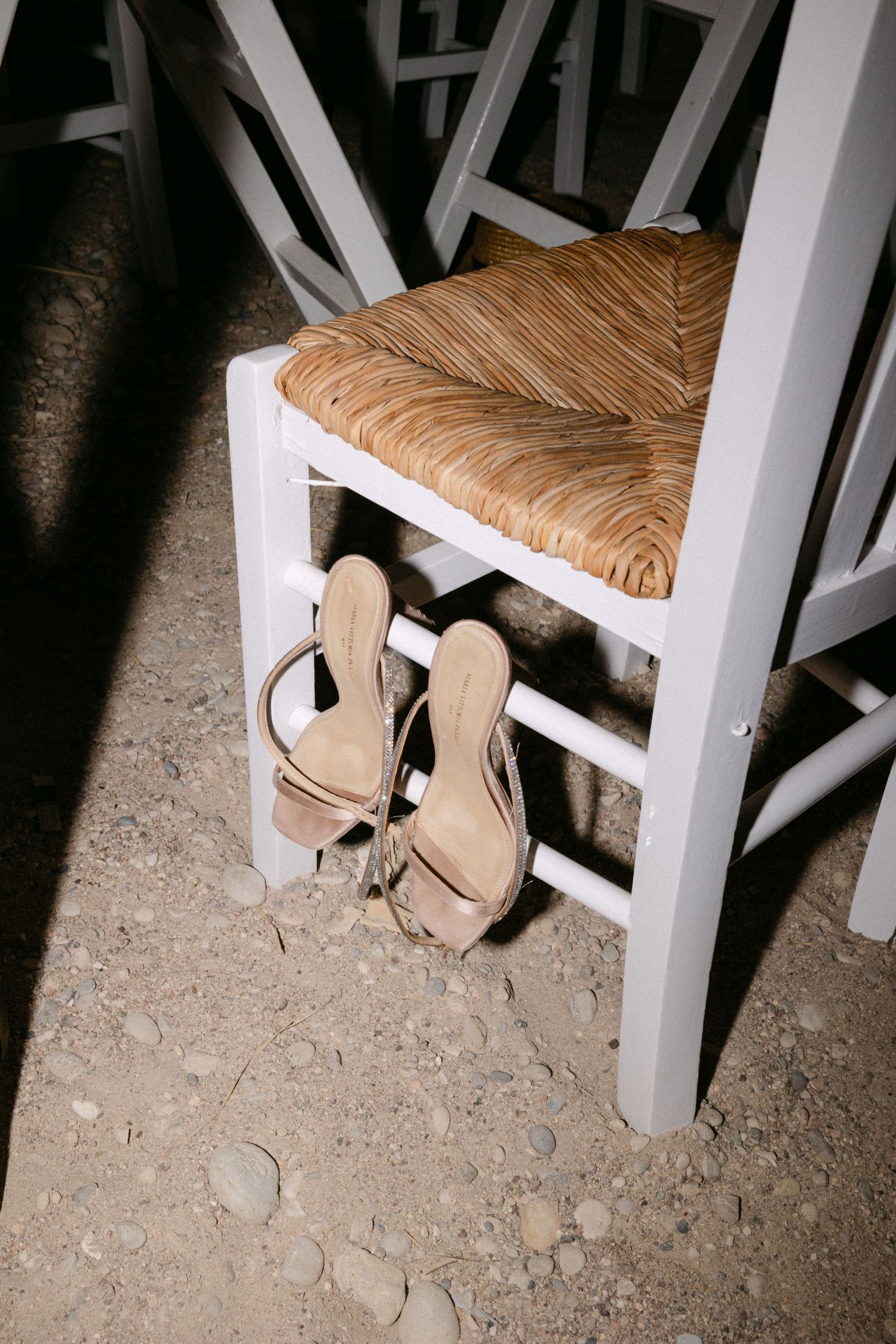 summer sandal shoes resting in a wooden chair in sand at night
