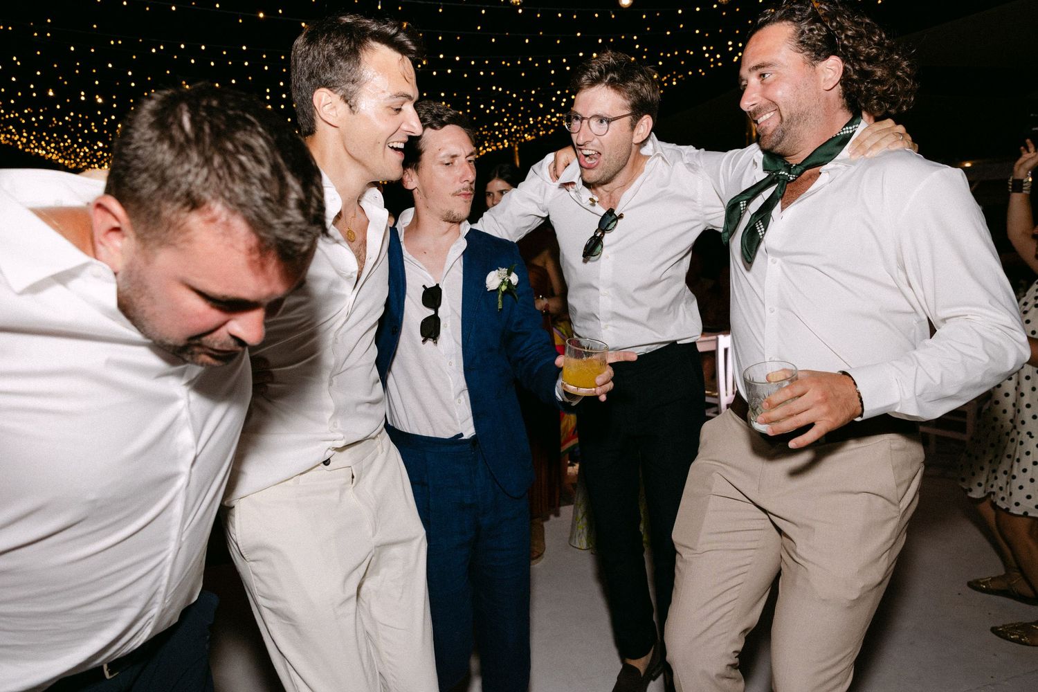 a groom and his four groomsmen sweaty dancing during a wedding party and singing loudly