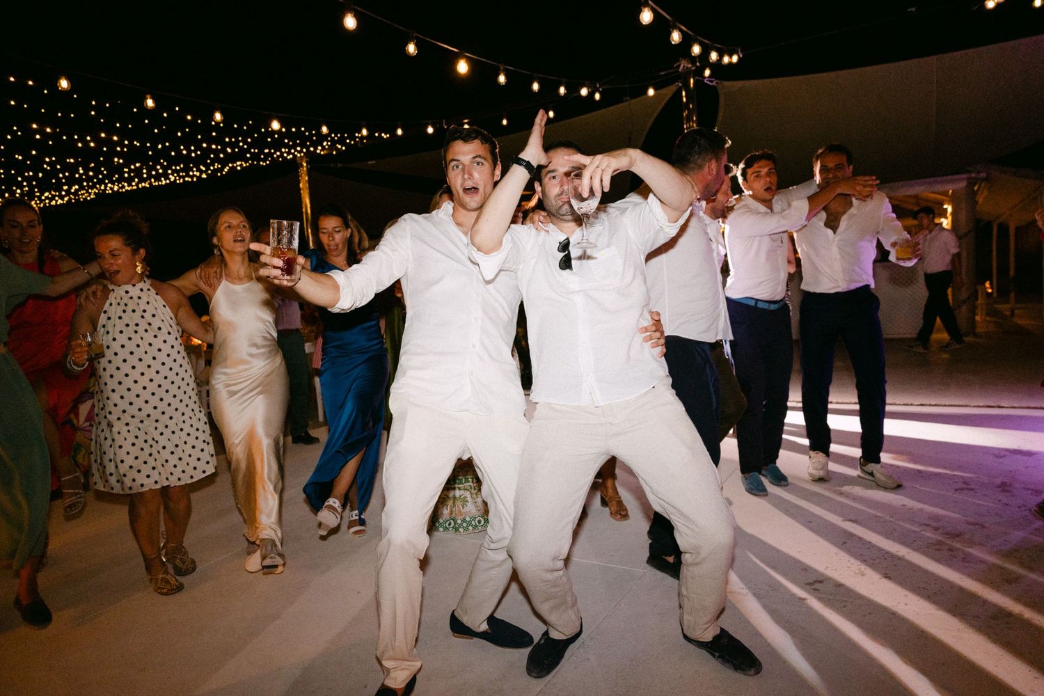 groom and guests dancing during the open-air wedding party of their Spetses wedding, laughing at the camera