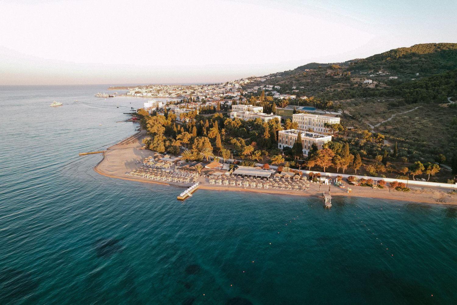 a drone photo showing Spetses where the sea is visible as well as greenery and a beach taken during sunset
