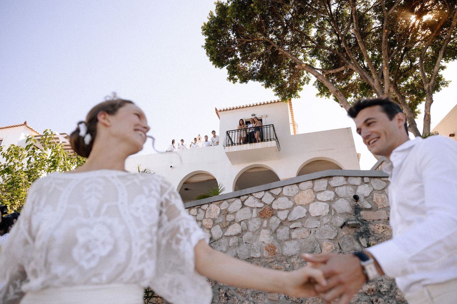 a bride and groom holding hands in a dancing pose while people are cheering in a c]background house