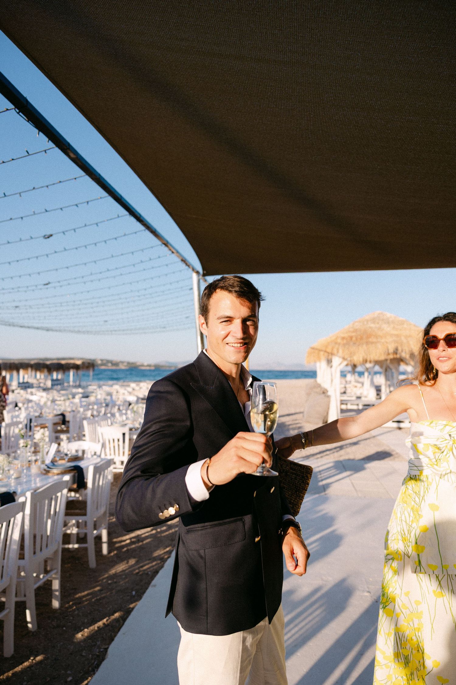 a groom toasting at the camera in a beach club