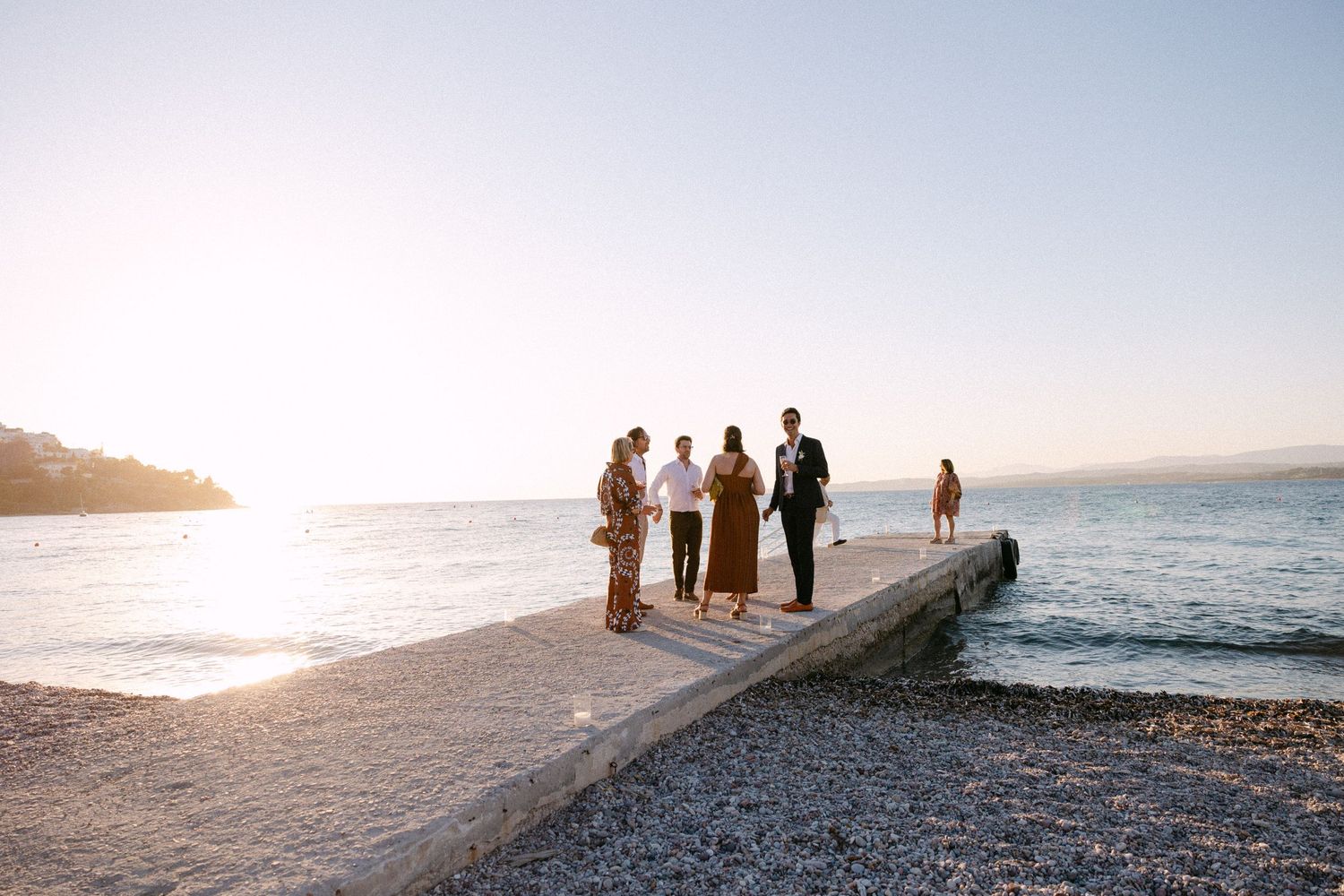 6 wedding guests at a dock during sunset chatting