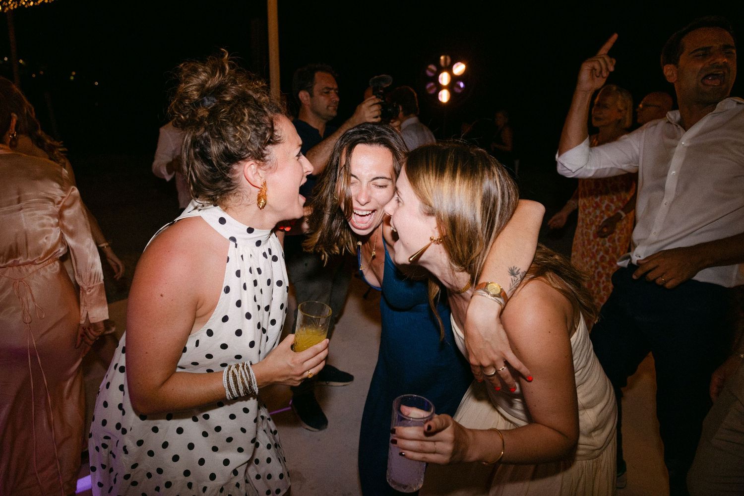 three wedding guests drunkenly singing in a summer wedding party
