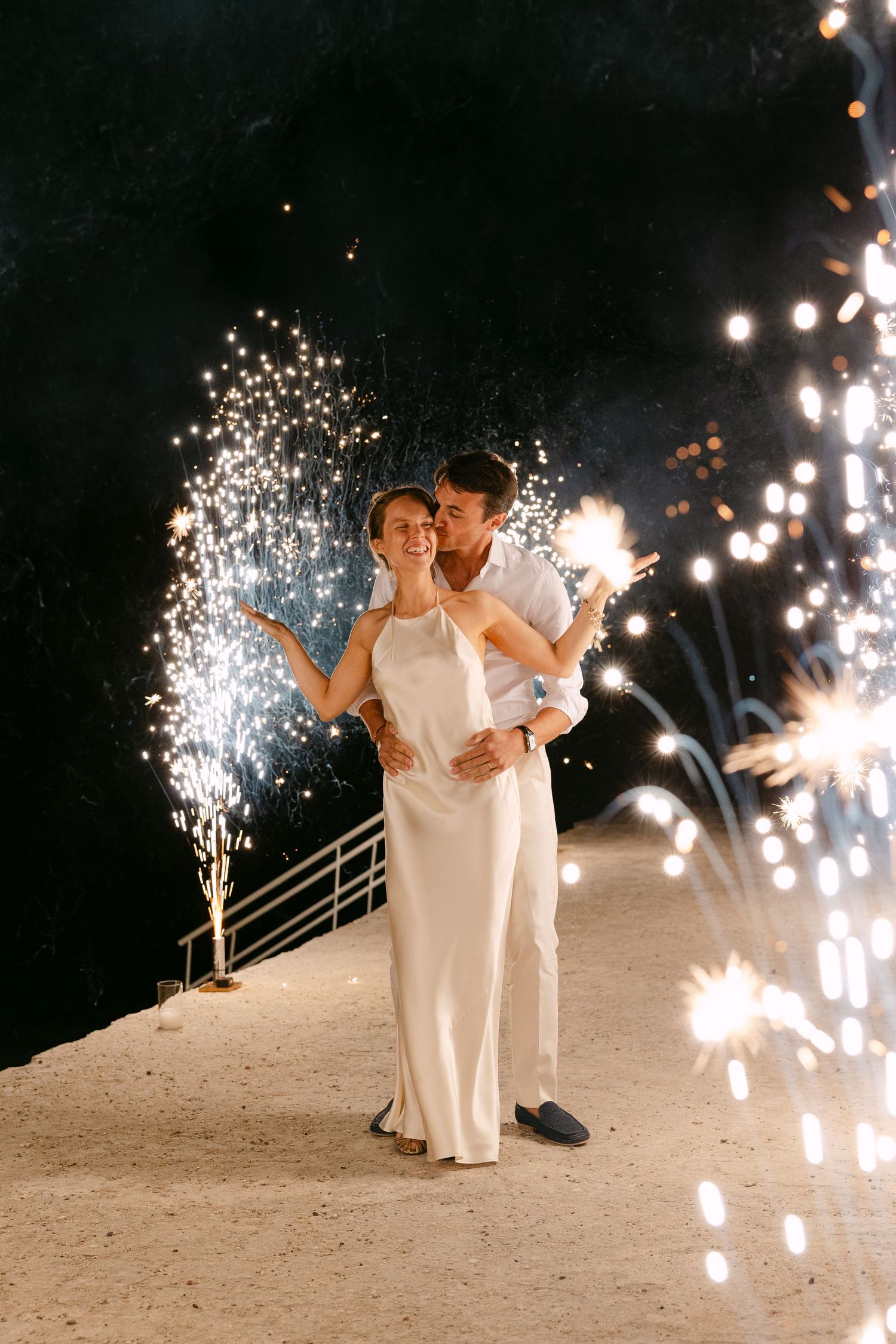 a bride and groom doing a grand entrance with ground fireworks, standing and the groom hugs the bride