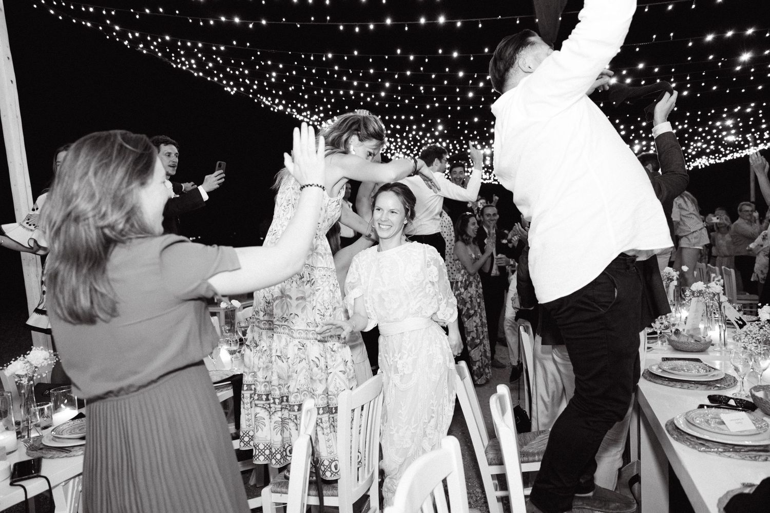 a black and white photo of a bride walking among cheering guests during the wedding's grand entrance