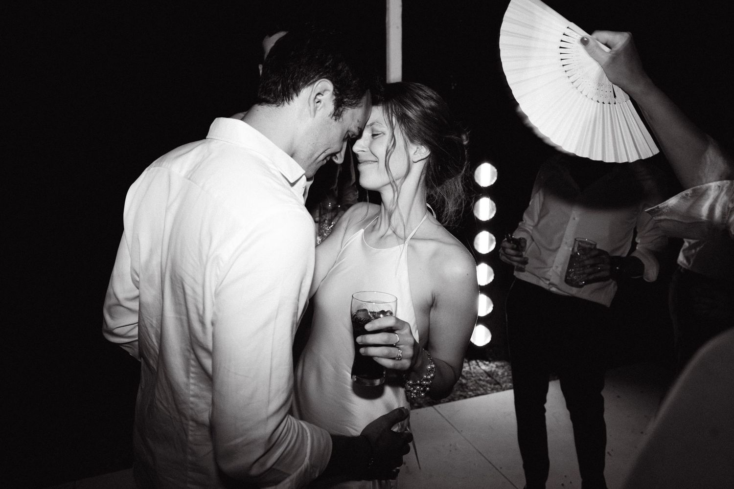 a black and white photo of a bride and groom dancing with each other during the open-air wedding party of their Spetses wedding