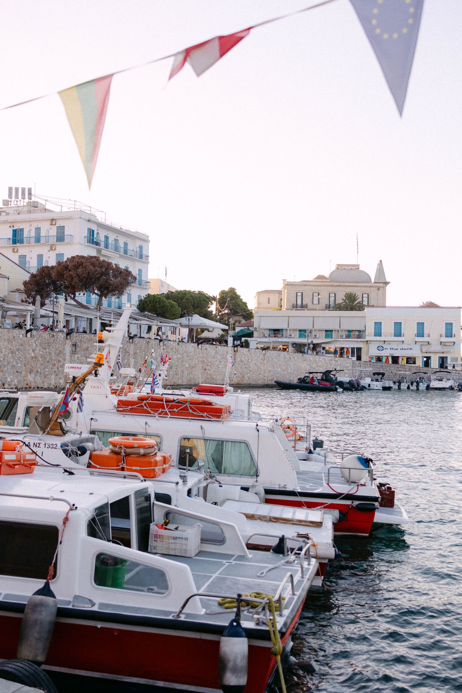 The Spetses port in golden hour - we see three red boats, houses in the background