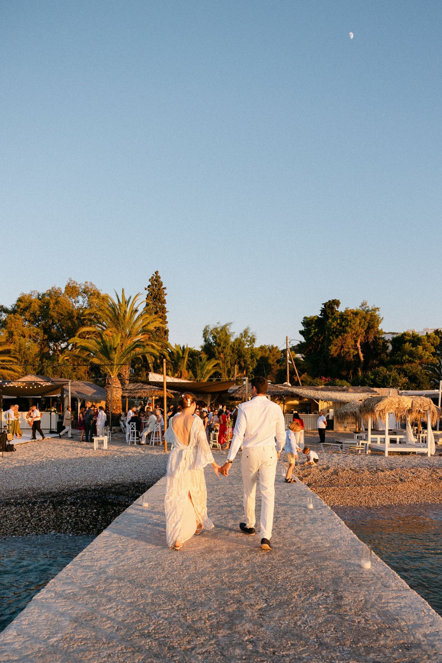 a bride and groom with their backs on the camera walking into a beach bar during their wedding cocktail hour in spetses, Greece