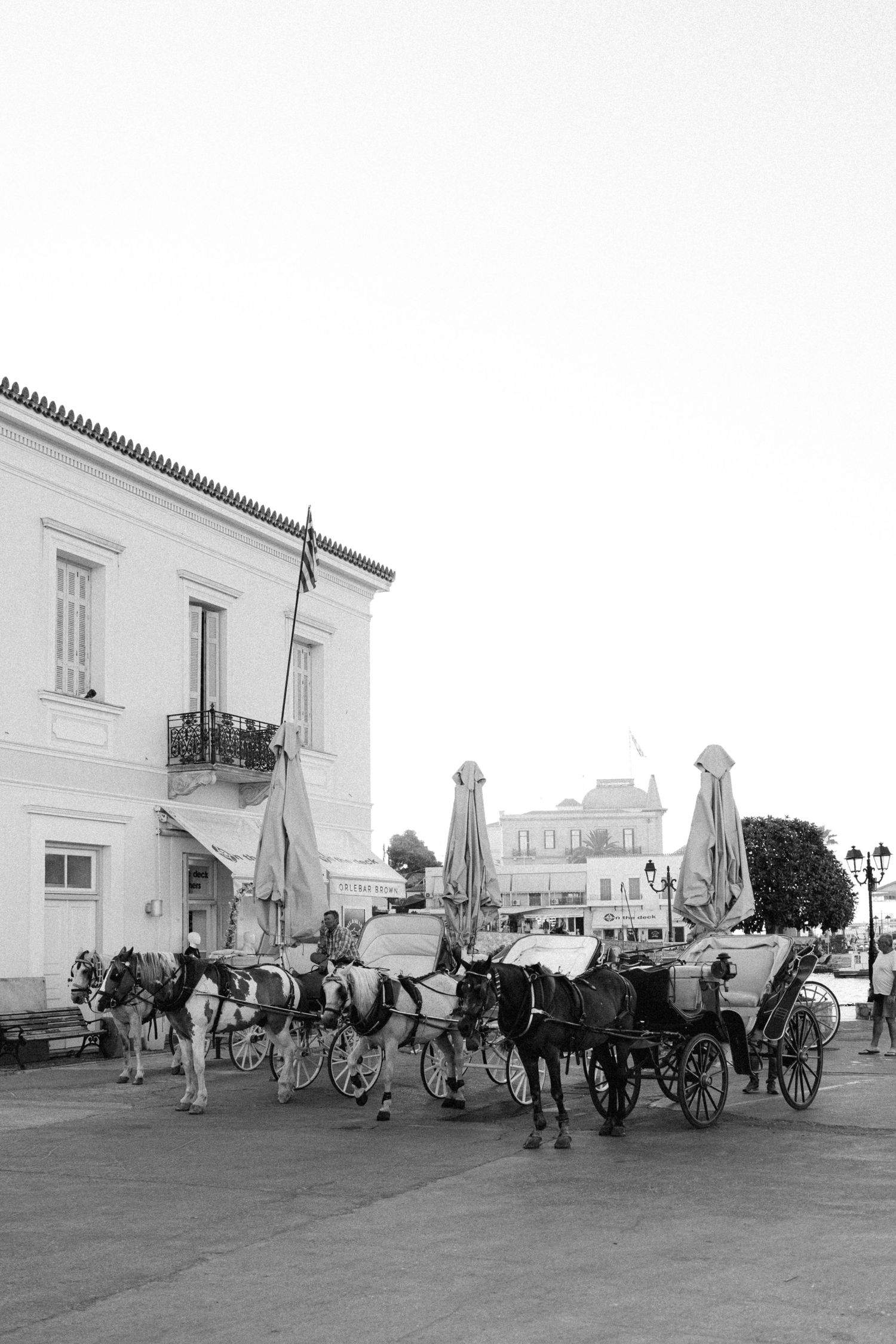 a black and white outdoor photo of horses and carriages in Spetses, Greece