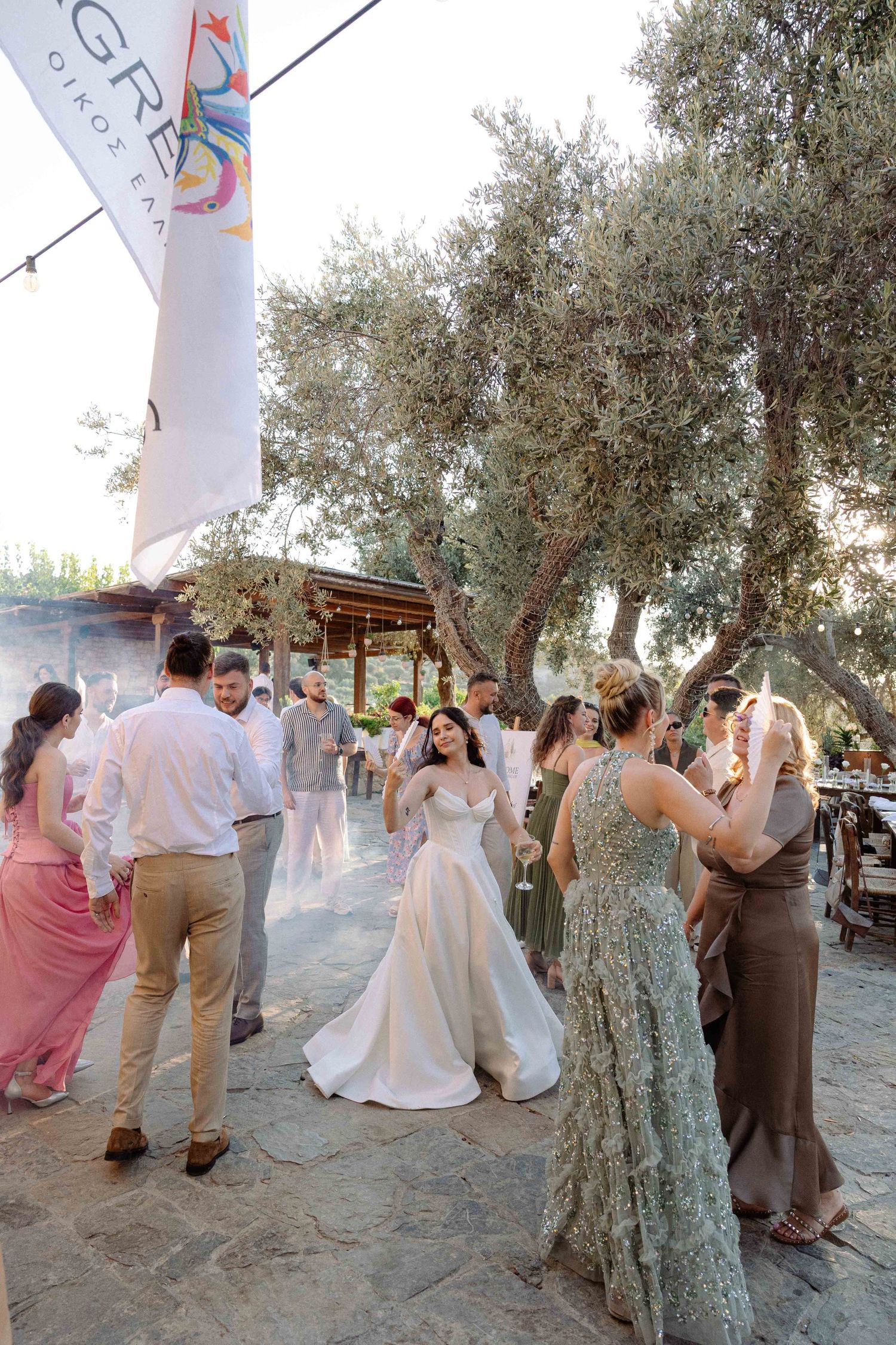 a party during a wedding reception - the guests and the bride are dancing at sunset in a nature rustic setting while still daylight exists