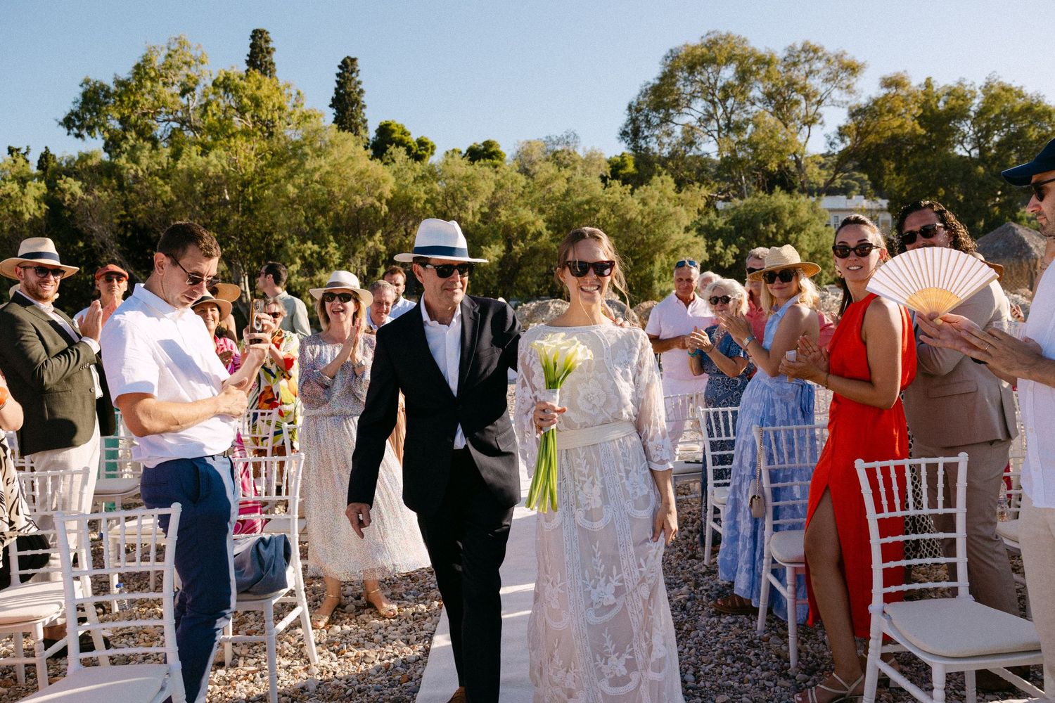 a dad walking his bride daughter towards the groom on their wedding ceremony, walking in the middle of the aisle while guests are cheering