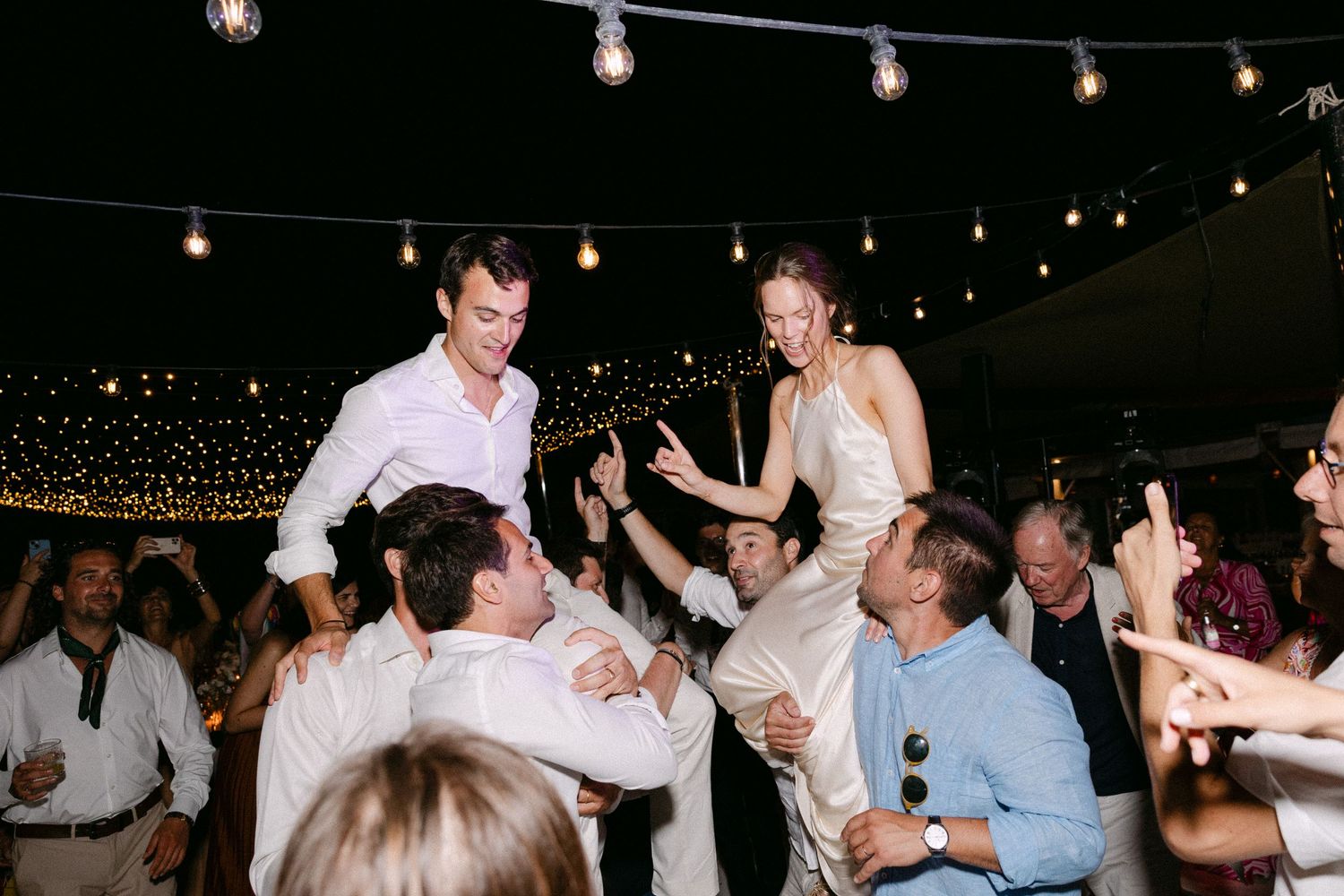 a bride and groom that guests have lift in the air during the party