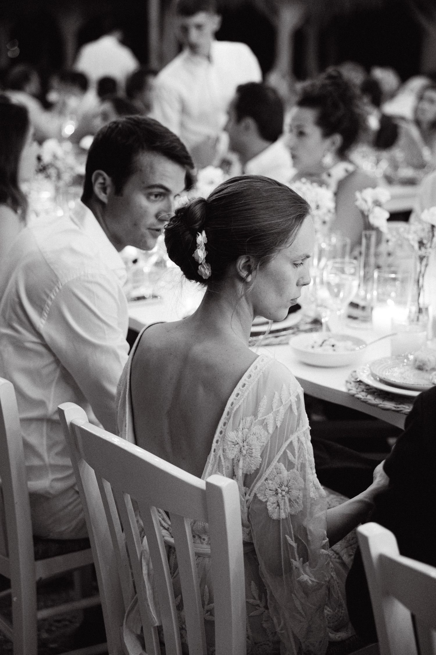 a black and white photo of a bride sitting on the wedding table, we see her side