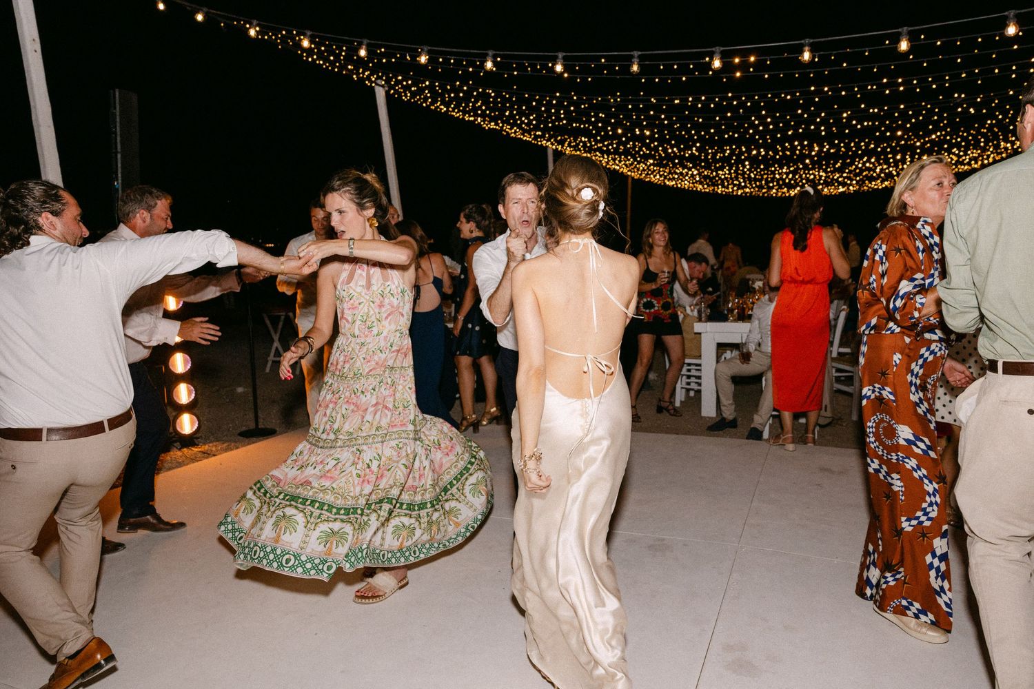 party photo of a bride wearing an open back dress and dancing with her back on the camera