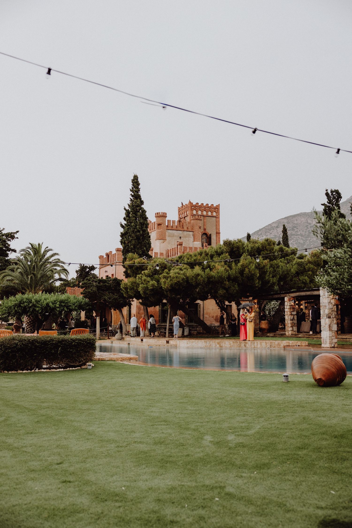 wide photo of the Pyrgos Melissourgou wedding venue located in the Athens Riviera, showing a castle, trees, grass and a pool