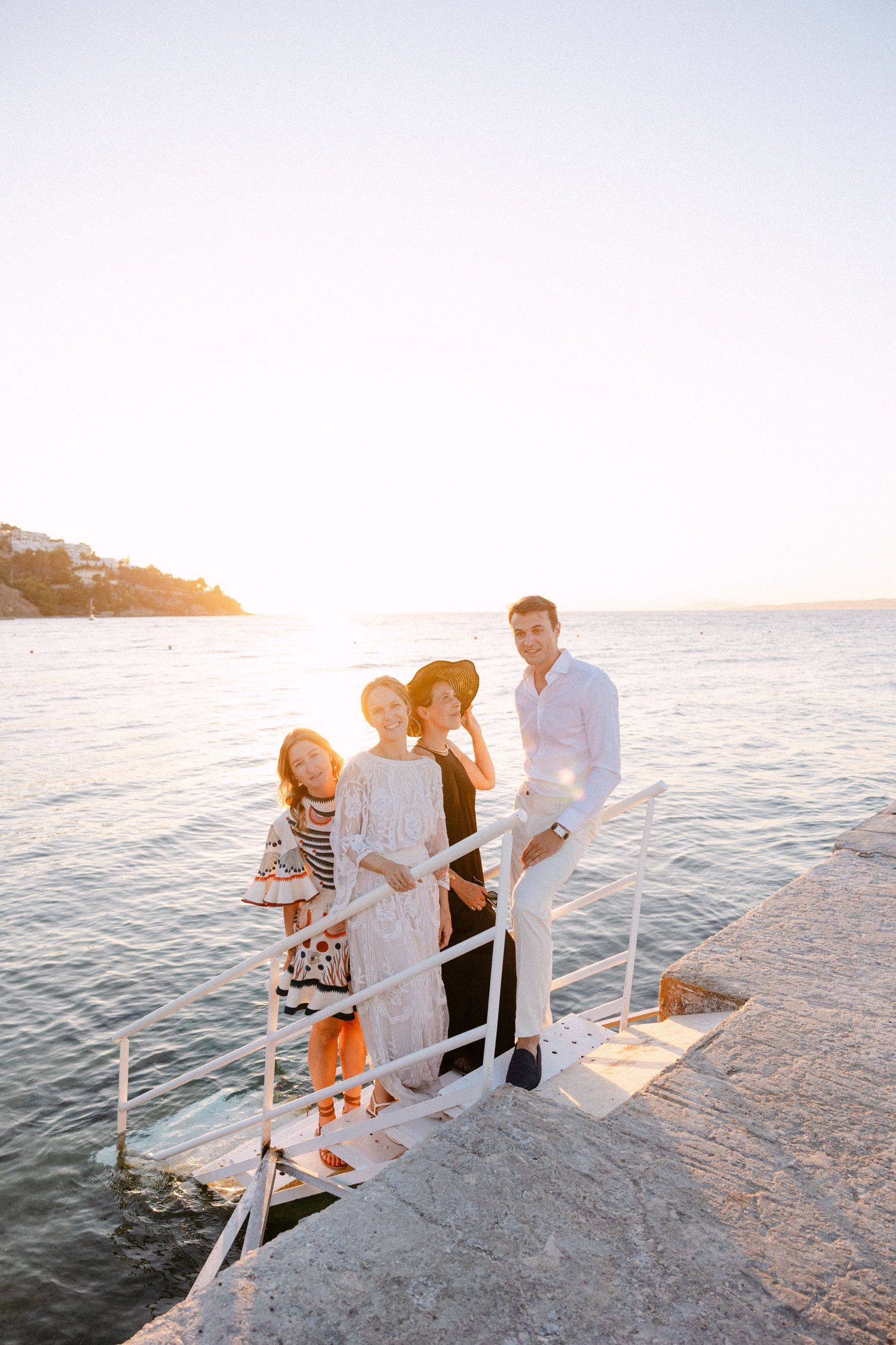 a bride, groom and 2 women in a dock at sunset smiling at the camera
